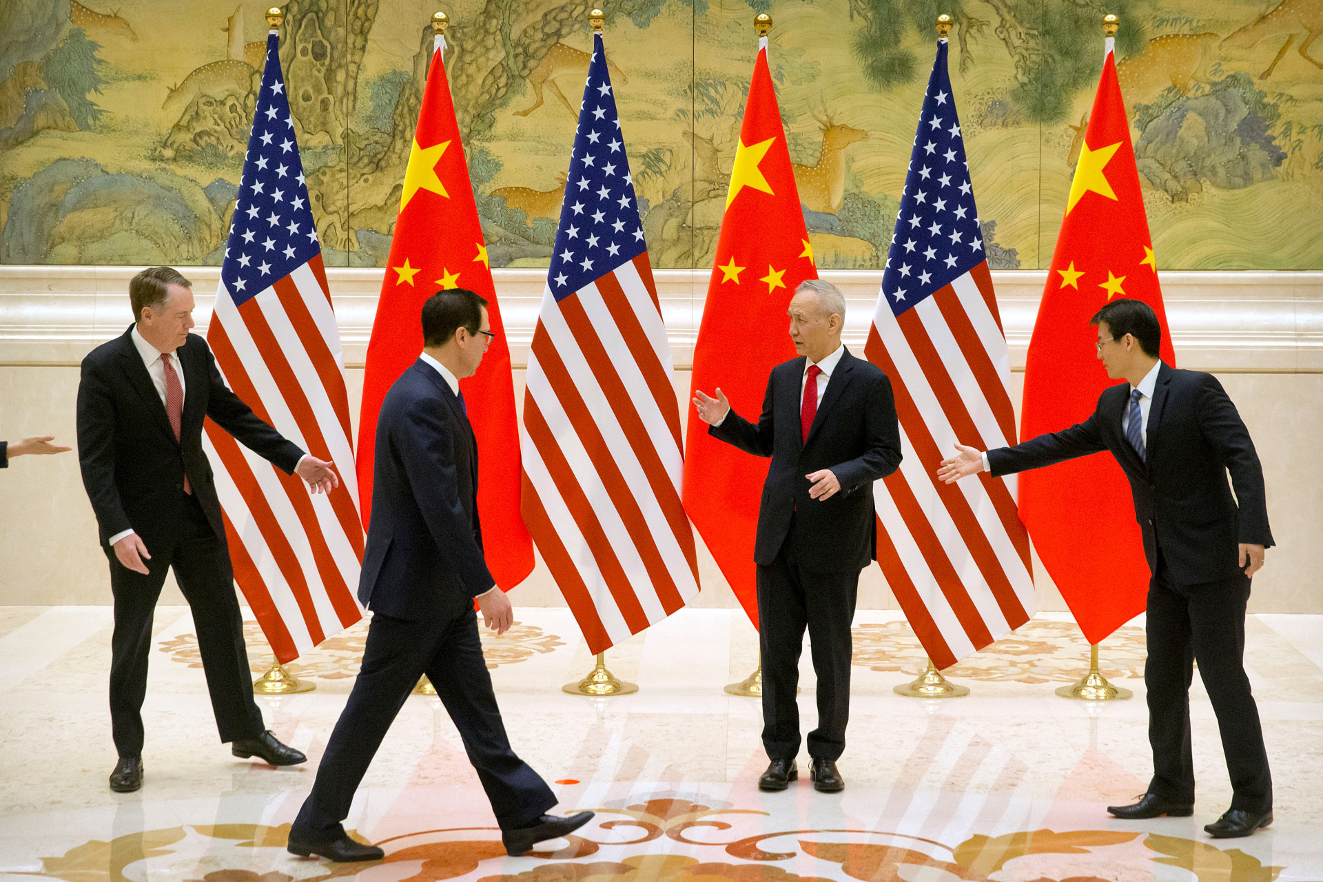 <p>Aides gesture as U.S. Trade Representative Robert Lighthizer, Chinese Vice Premier and lead trade negotiator Liu He, and U.S. Treasury Secretary Steven Mnuchin line up for a photo before the opening session of trade negotiations at the Diaoyutai State Gue</p>

