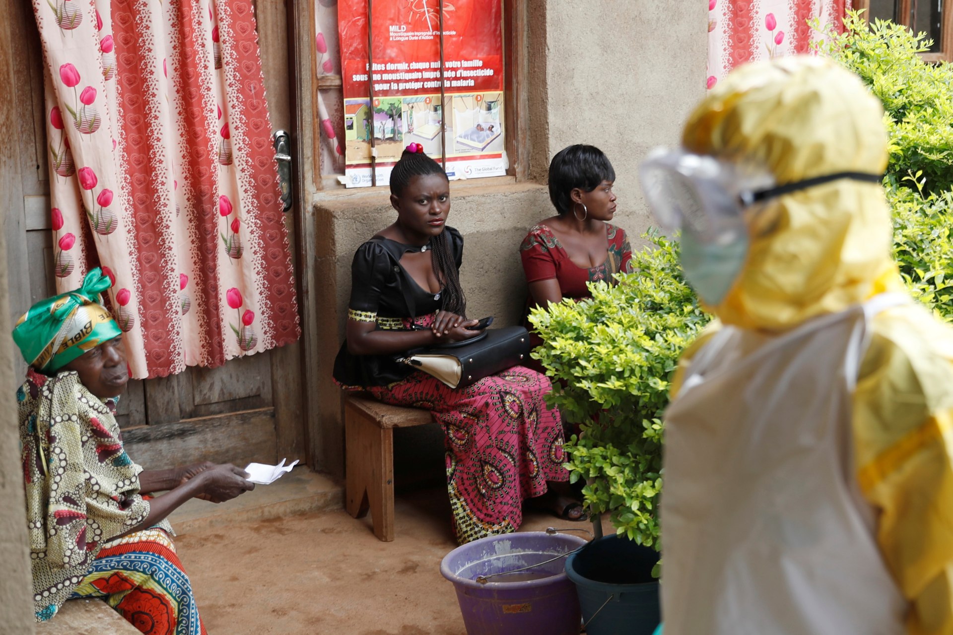 <p>Women sit as healthcare workers enter a room where is a baby suspected of dying of Ebola in Beni, North Kivu Province of Democratic Republic of Congo, on December 13, 2018.</p>
