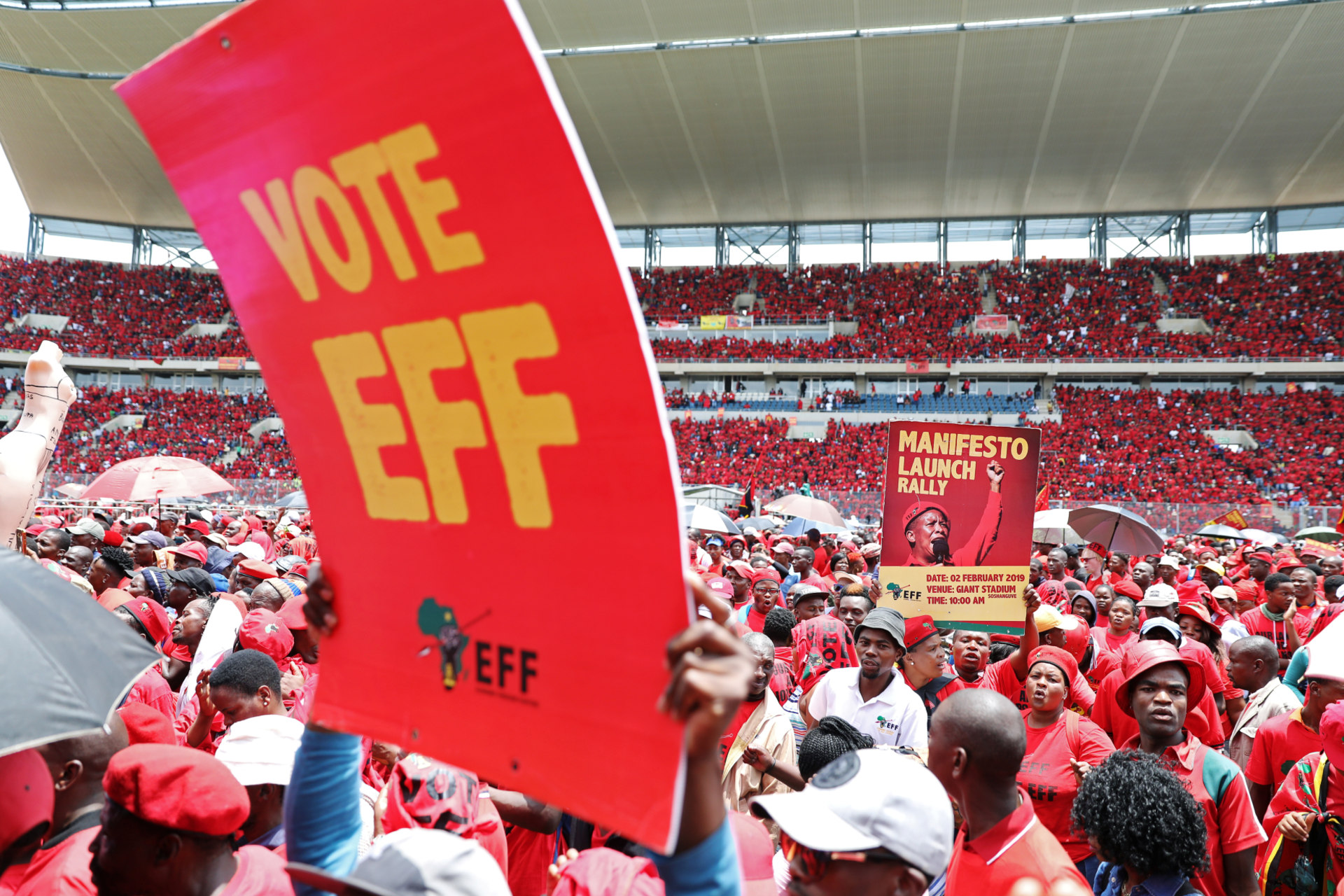 <p>Supporters of South Africa’s radical left-wing party, the Economic Freedom Fighters (EFF), hold a placard during the launch of the party’s election manifesto in Soshanguve, near Pretoria, South Africa, on February 2, 2019. </p>
