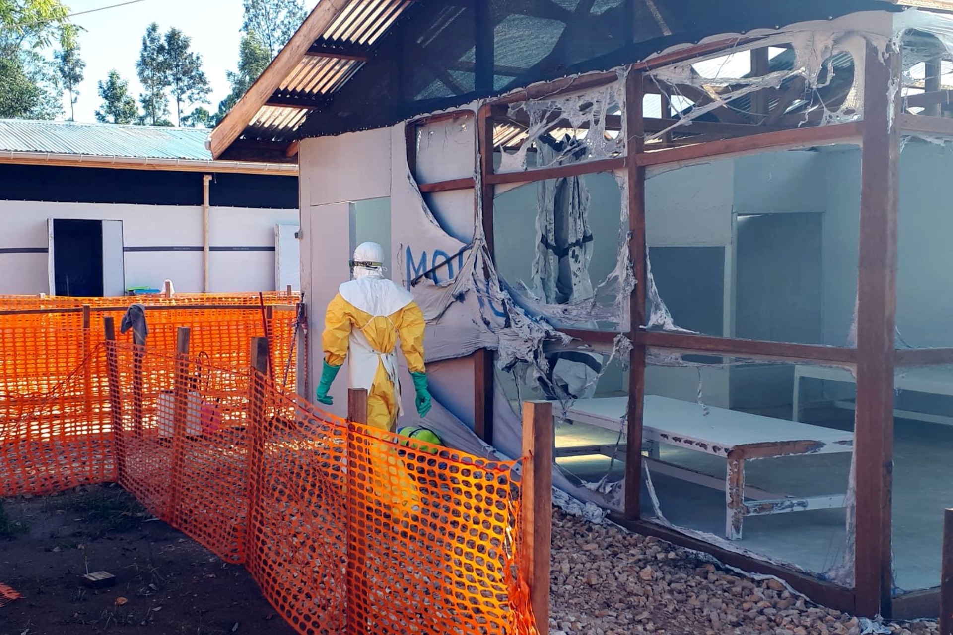 <p>A health worker dressed in a protective suit walks past burned structures after attackers set fire to an Ebola treatment center run by Medecins Sans Frontieres (MSF) in the east Congolese town of Katwa, Democratic Republic of Congo, on February 25, 2019.</p>
