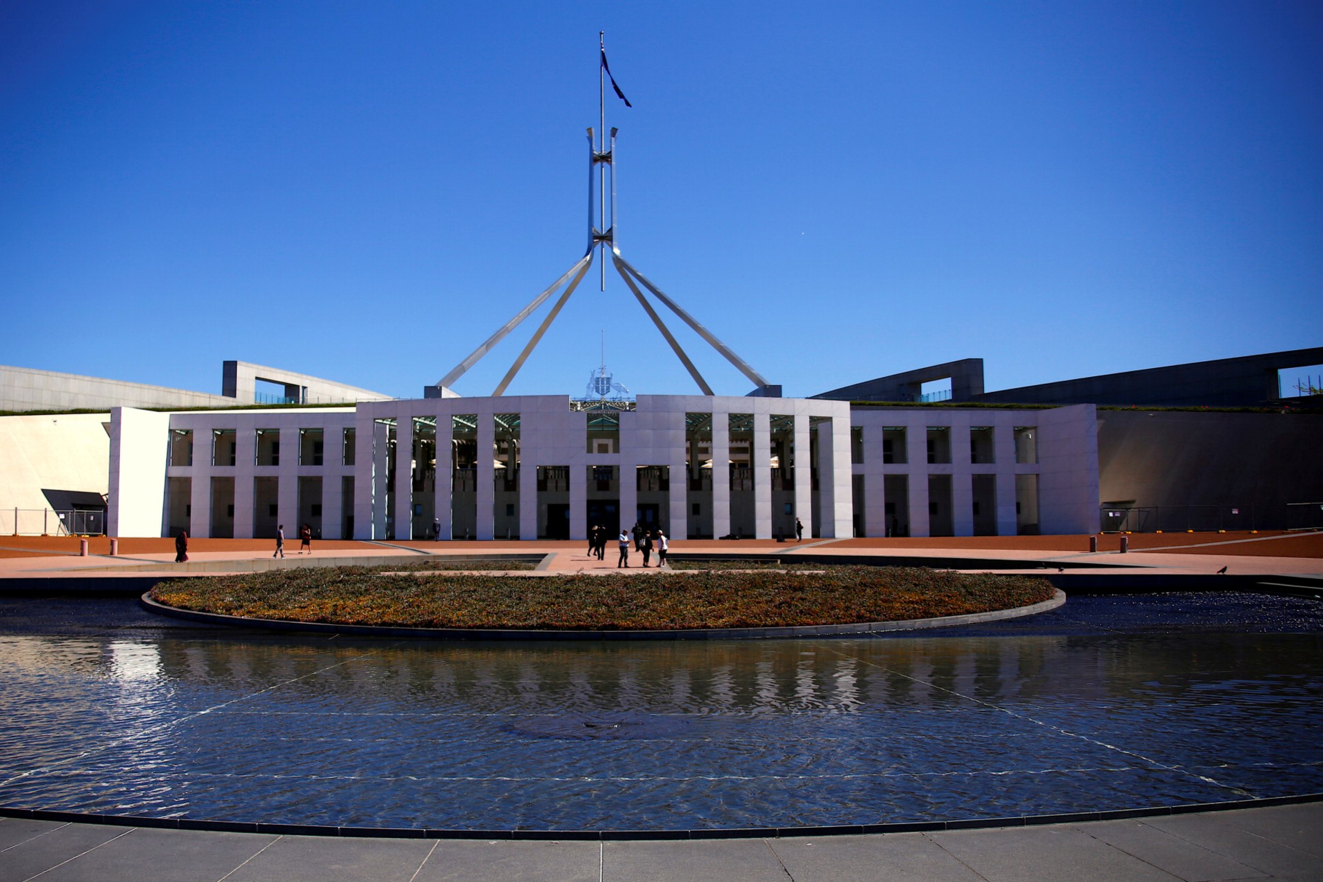 <p>Tourists walk around the forecourt of Australia’s Parliament House in Canberr</p>
