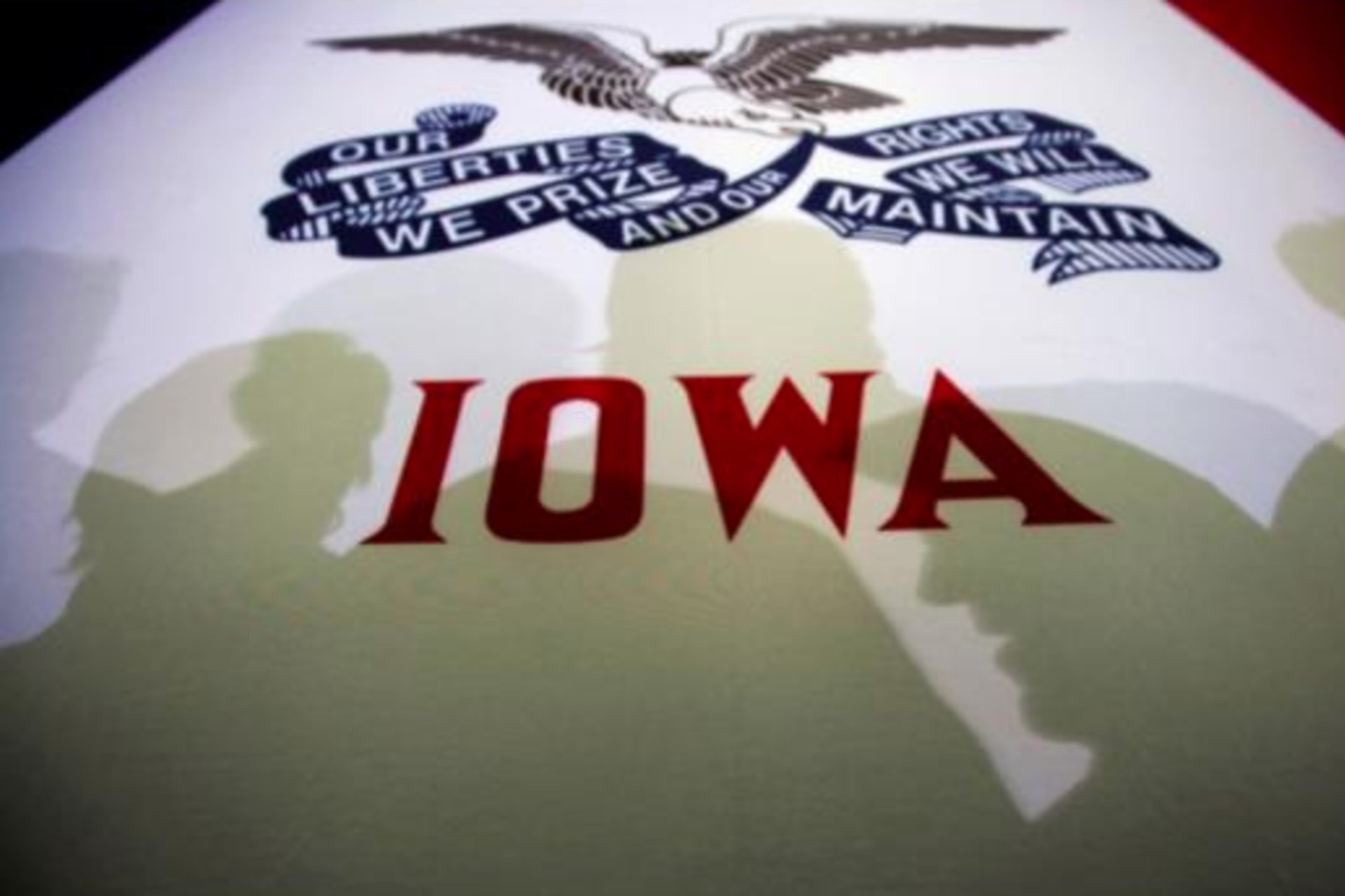 <p>Potential caucus voters cast shadows on an Iowa state flag at a campaign rally in Clive, Iowa, January 2, 2012.</p>