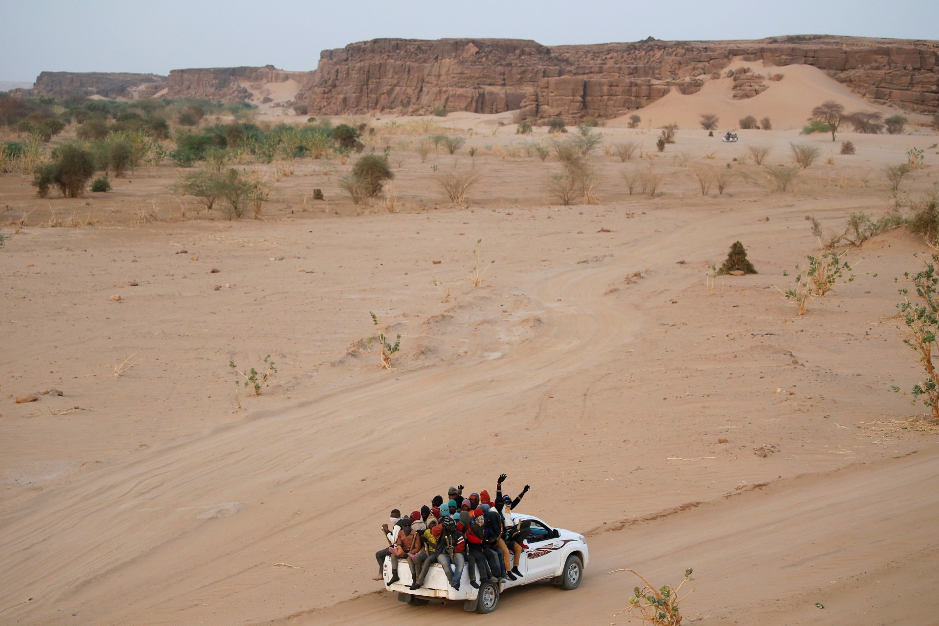 <p>Migrants crossing the Sahara desert into Libya ride on the back of a pickup truck outside Agadez, Niger, on May 9, 2016. </p>