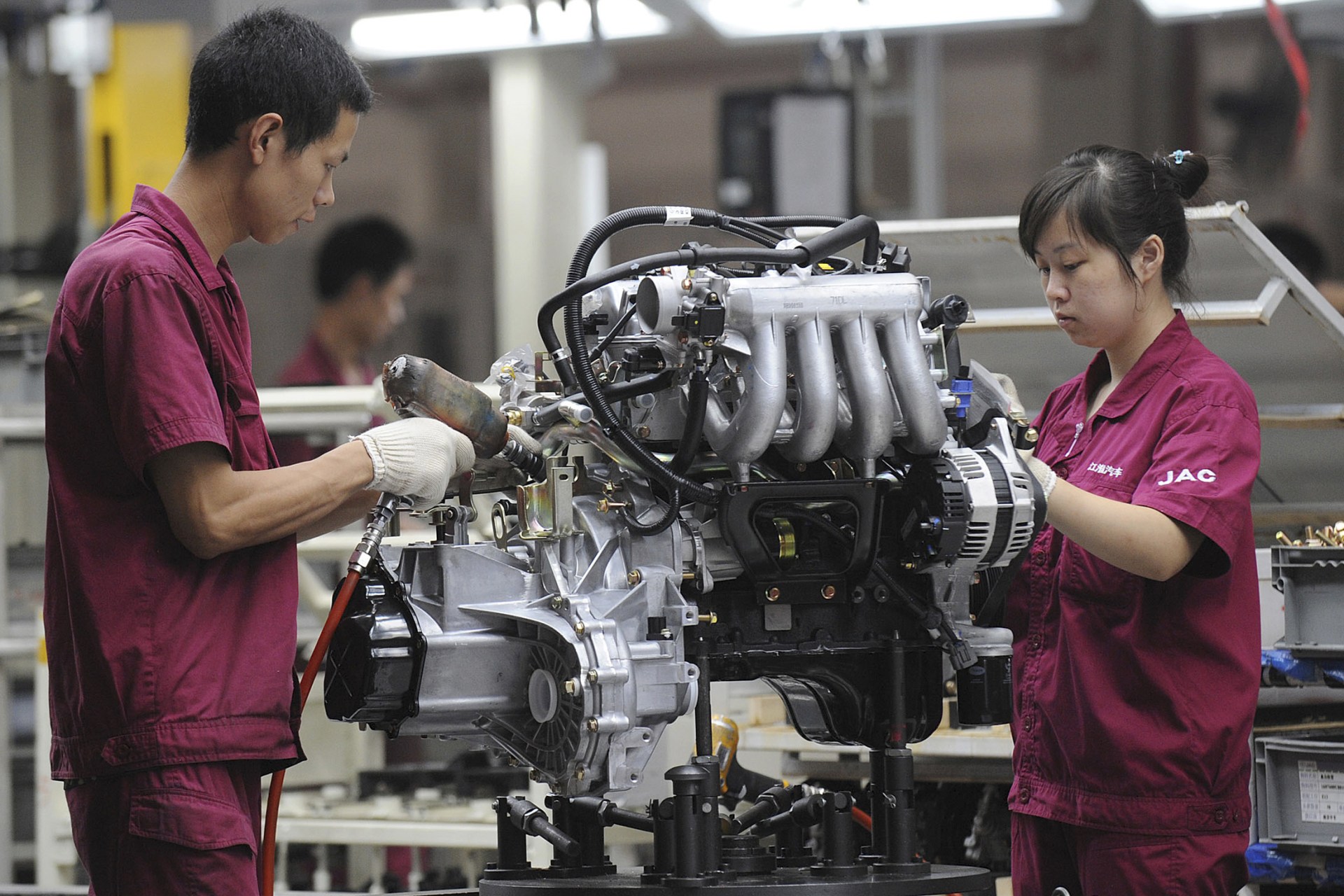 <p>Employees assemble an engine at the production line of an automobile company in Anhui province, China. July 16, 2009.</p>