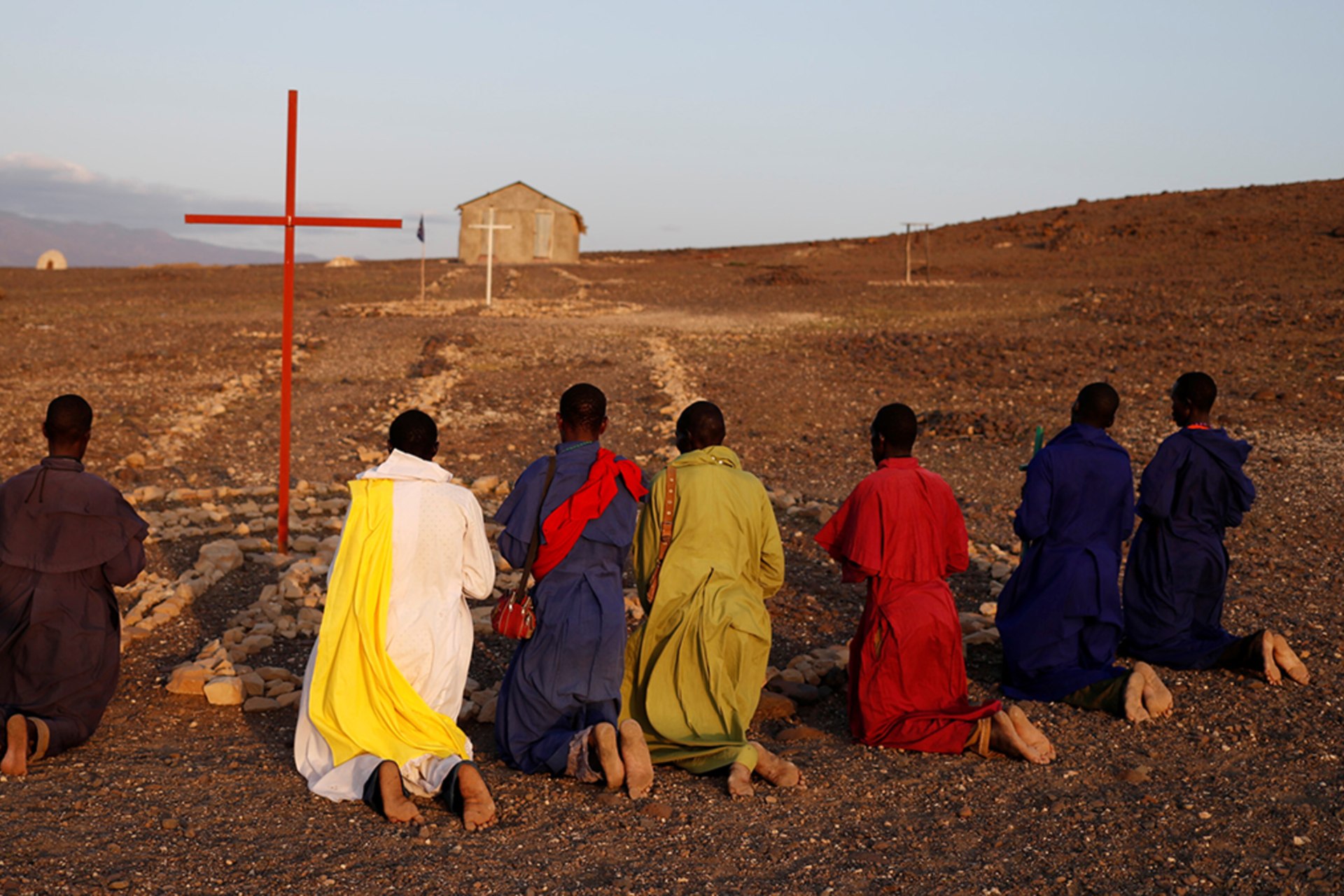 <p>Turkana men pray outside a Legio Maria African Mission Church in Loiyangalani, Kenya, on August 5, 2017.</p>
