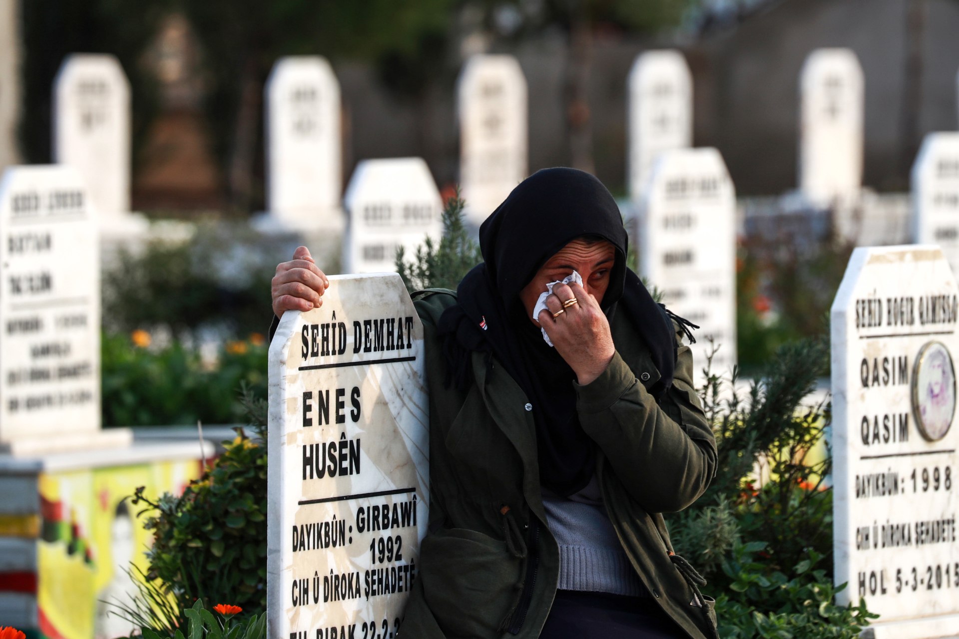 <p>A Syrian Kurdish woman hugs the tombstone of a fallen Syrian Democratic Forces fighter at a cemetery in Qamishli.</p>