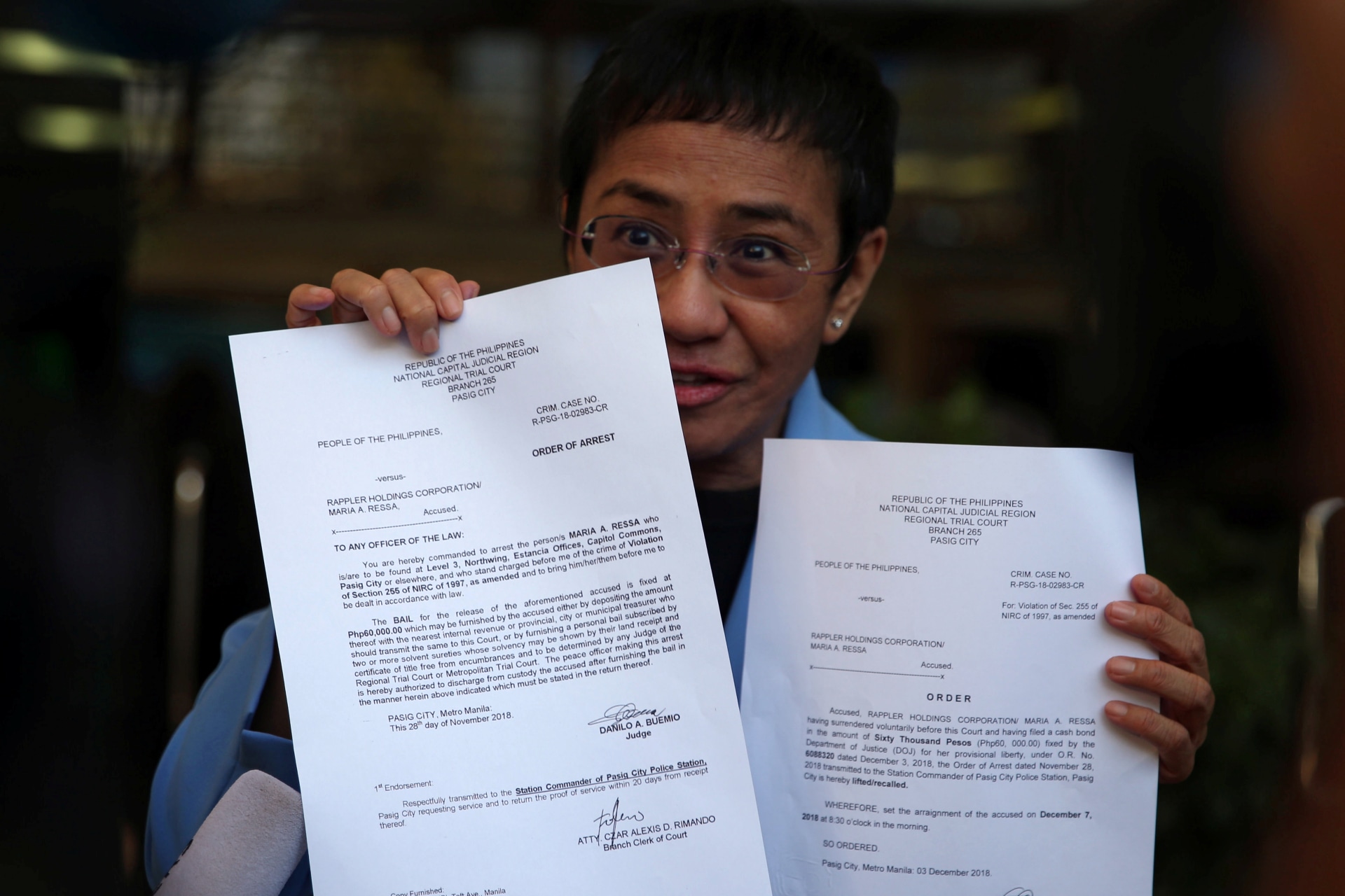 <p>Maria Ressa, an executive of online news platform Rappler, shows her arrest warrant and release order after posting bail for tax evasion charges at Regional Trial Court Branch 265 in Pasig City, Metro Manila, in Philippines, on December 3, 2018.</p>