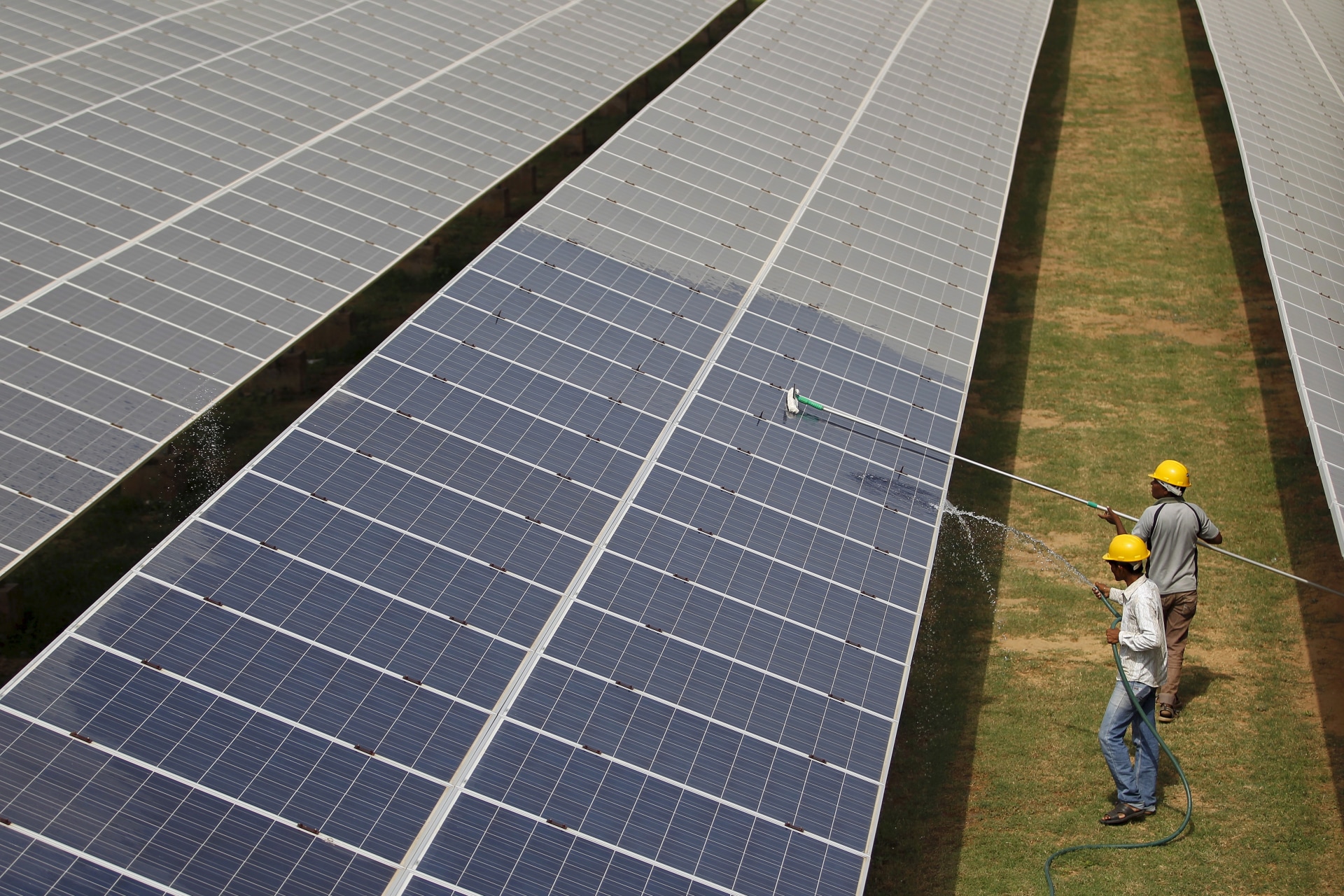 <p>Workers clean photovoltaic panels inside a solar power plant in Gujarat, India.</p>
