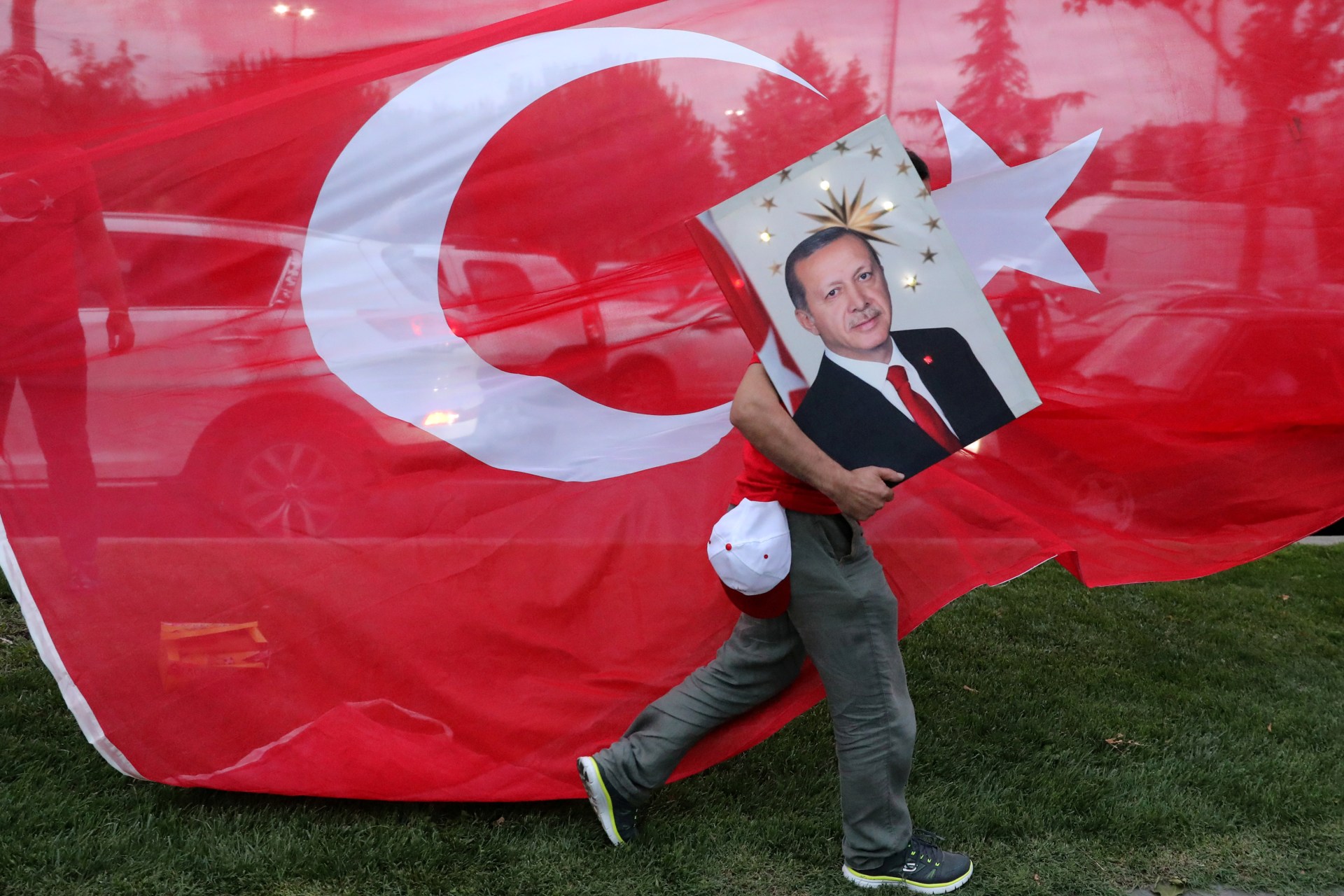 <p>A supporters of Turkish President Tayyip Erdogan holds his picture in front of a Turkish flag, in front of Turkey’s ruling AK Party (AKP) headquarters in Istanbul,Turkey, June 24, 2018.</p>
