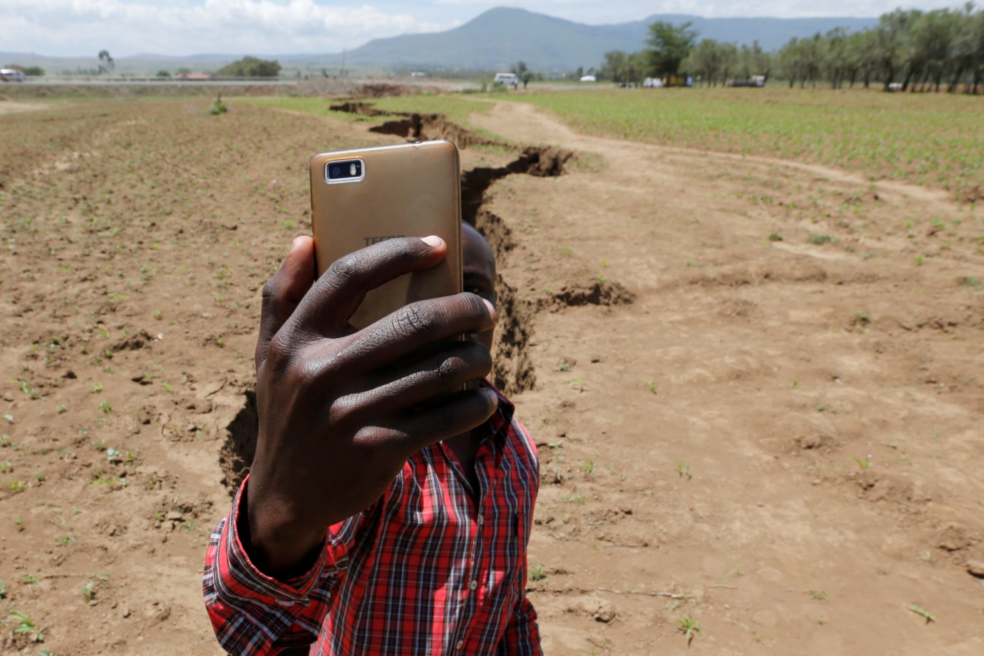 <p>A man holds his phone to take a Facebook live video near a chasm suspected to have been caused by a heavy downpour along an underground fault-line near the Rift Valley town of Mai Mahiu, Kenya March 28, 2018.</p>

