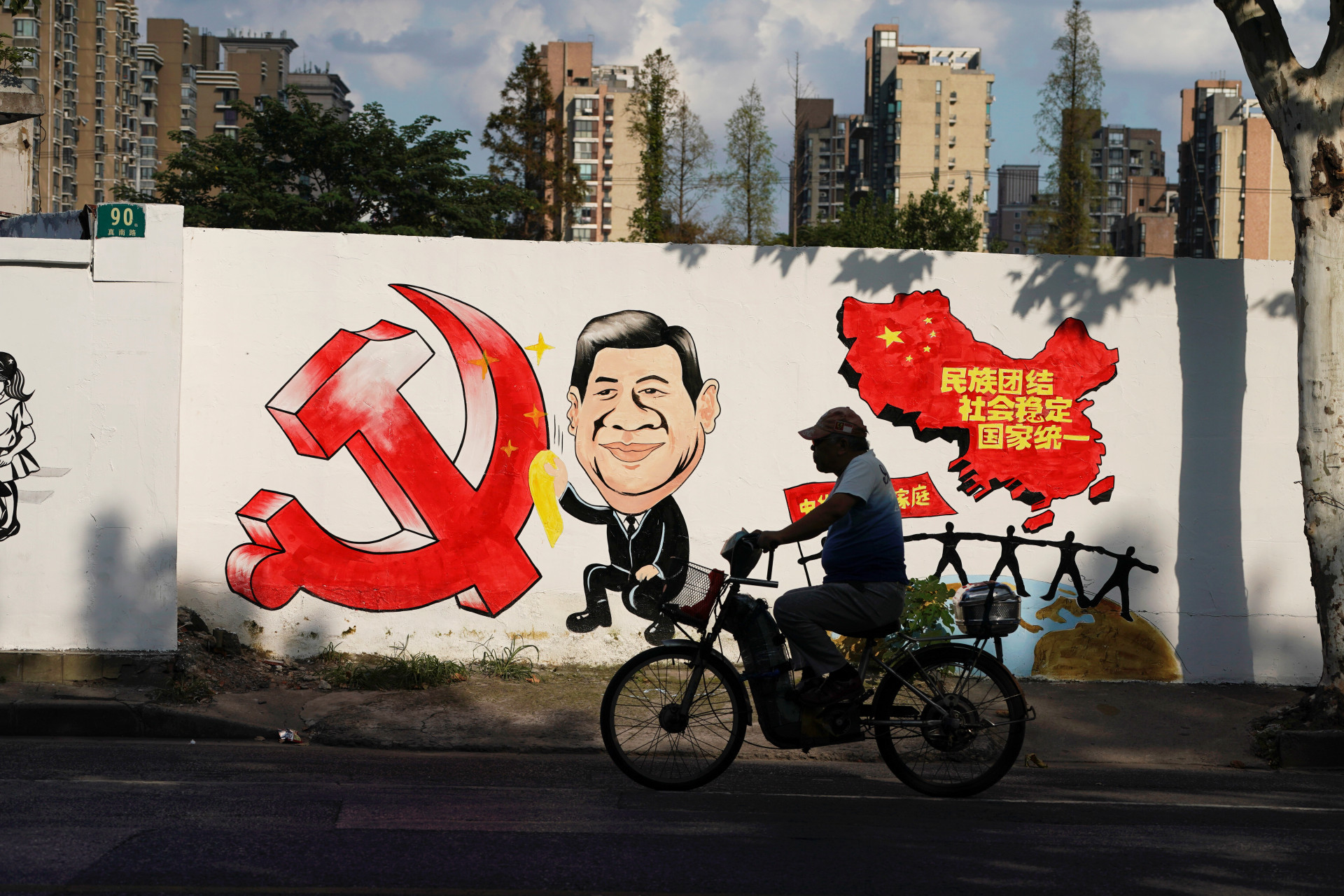 <p>A man rides a bicycle next to a mural showing an image of Chinese President Xi Jinping along a street in Shanghai, China September 28, 2018. </p>

