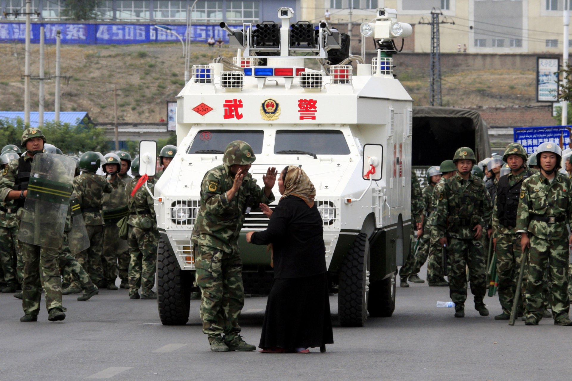 <p>A woman on a crutch argues with a Chinese paramilitary police in front of an armoured personnel carrier in the city of Urumqi in China’s Xinjiang Autonomous Region in 2009.</p>
