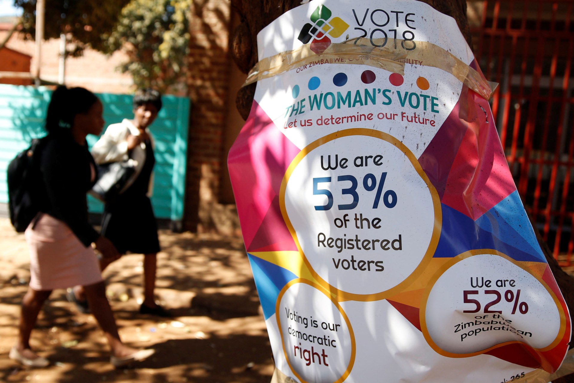 <p>Women walk past Zimbabwe Electoral Commission (ZEC) posters in Harare, Zimbabwe, July 26, 2018. </p>