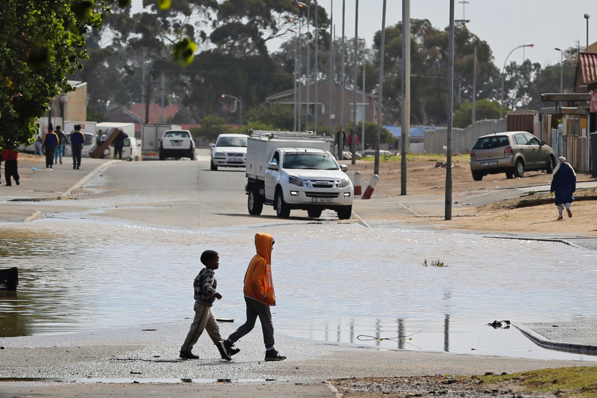 <p>Children walk past a puddle after heavy rains in drought-hit Cape Town, South Africa, April 26, 2018. When it does rain, drought conditions increase the likelihood of flooding as dry, compacted soil is less able to absorb water.</p>

