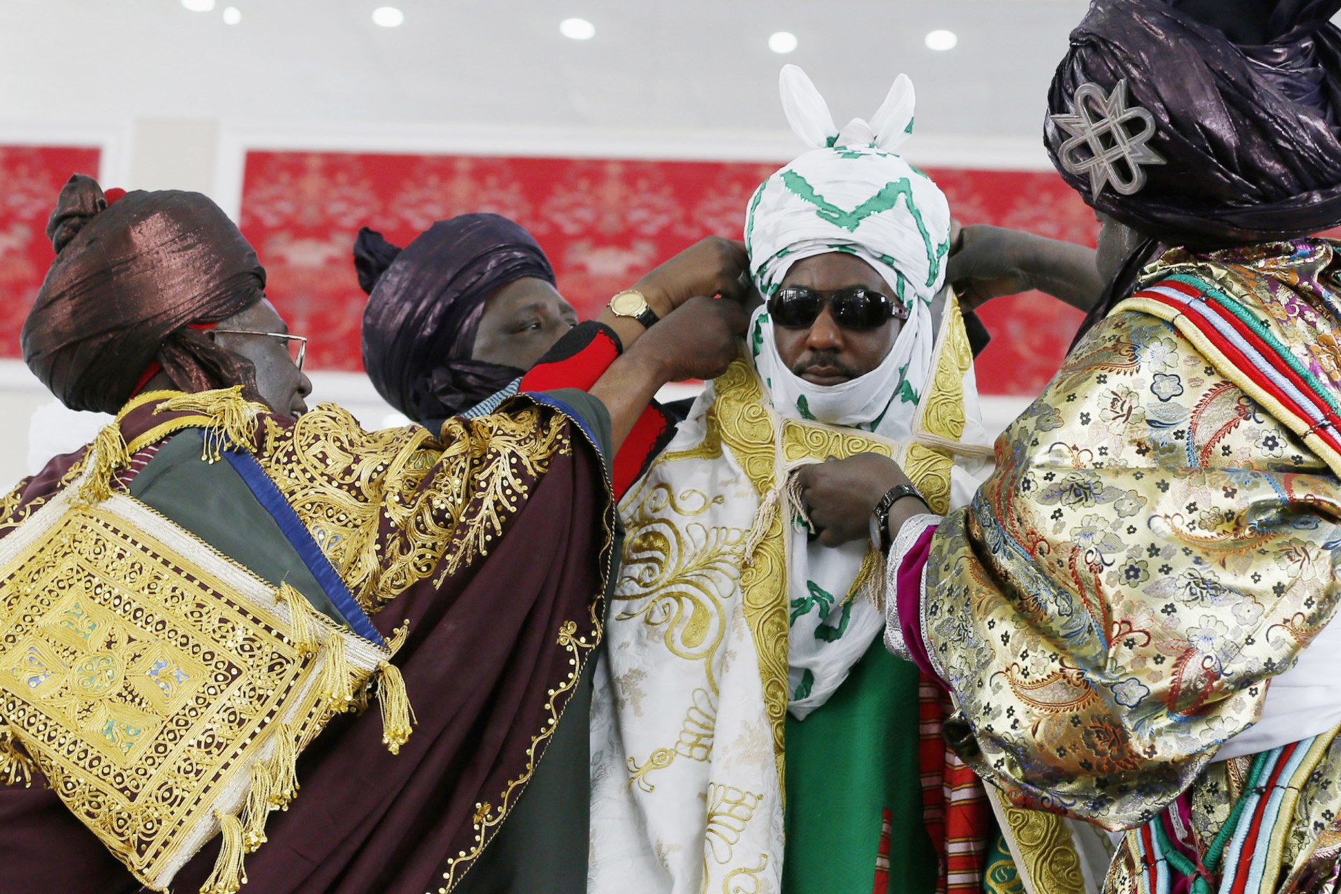 <p>New Emir of Kano Muhamadu Sanusi II ( 2nd R) is dressed by the Kingmakers, a traditional role charged with officially dressing the king, during his coronation in Kano, Kano State, February 7, 2015. </p>
