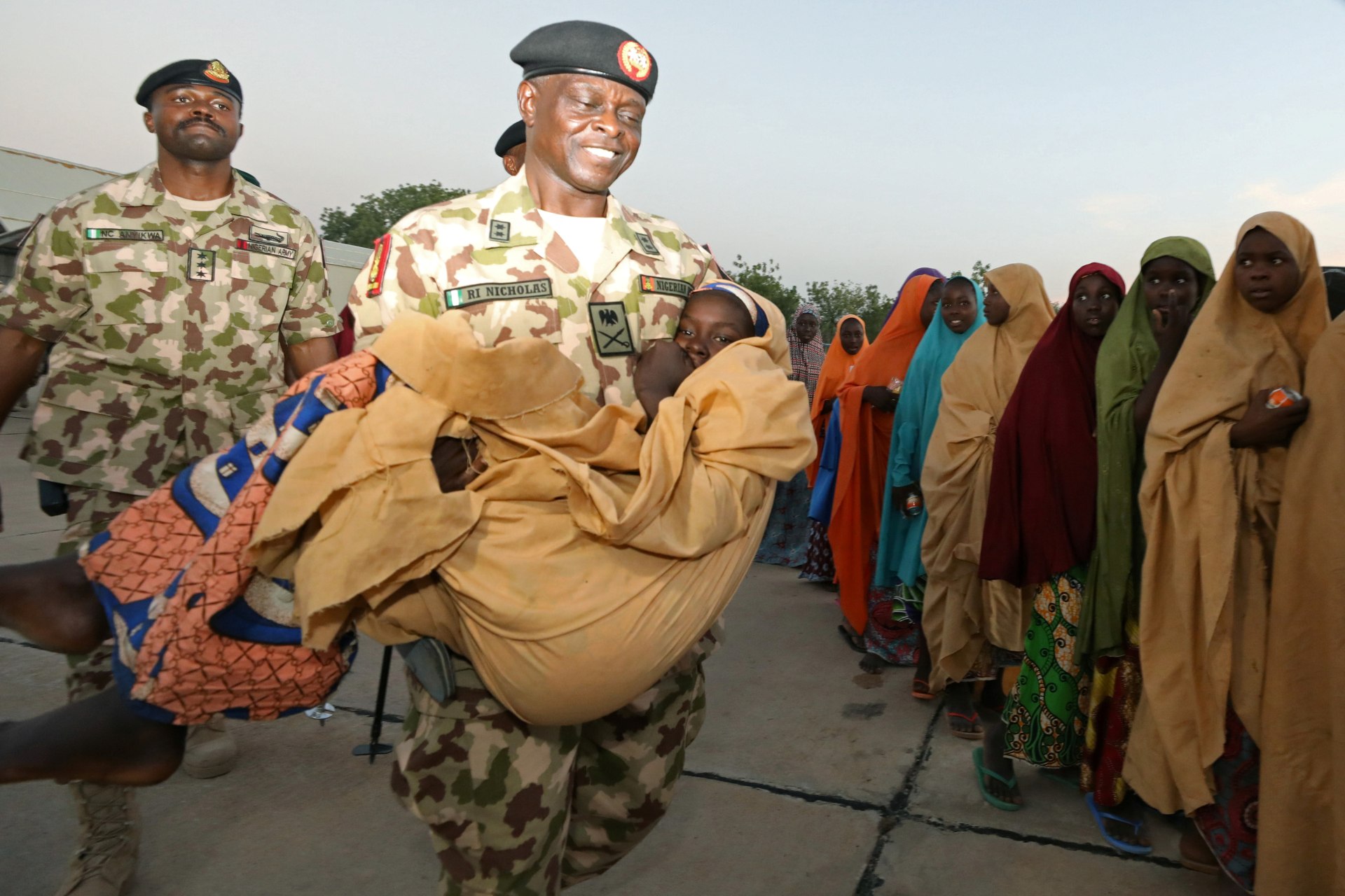 <p>Major General Rogers Nicholas, Theatre commander, Operation Lafiya Dole, carries one of the newly released Dapchi schoolgirls as others wait for boarding a plane at the air force base in Maiduguri, Nigeria March 21, 2018. </p>
