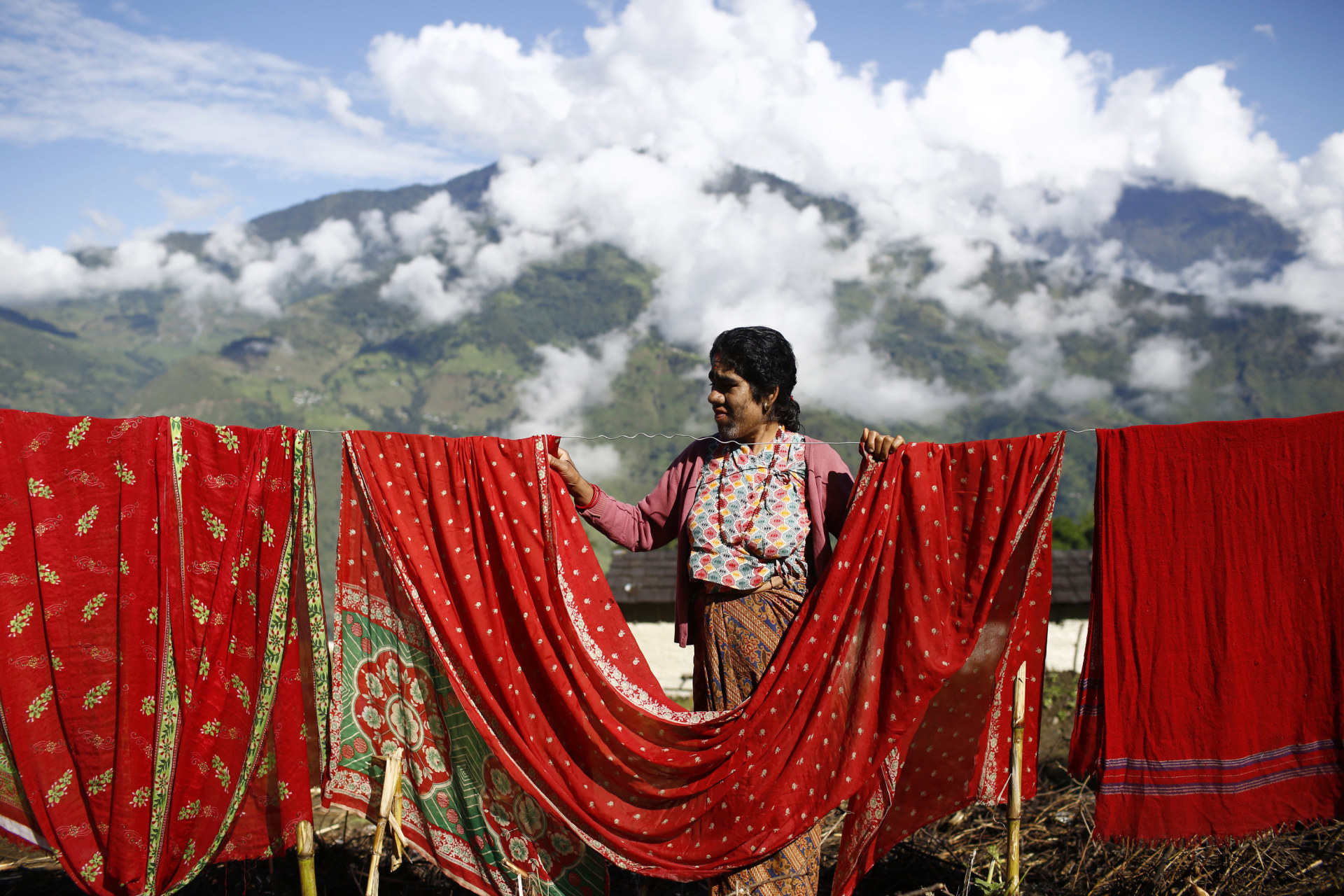 <p>Devi Budhathoki, 38, dries her clothes outside her house in Kharay, Dolkha District.</p>
