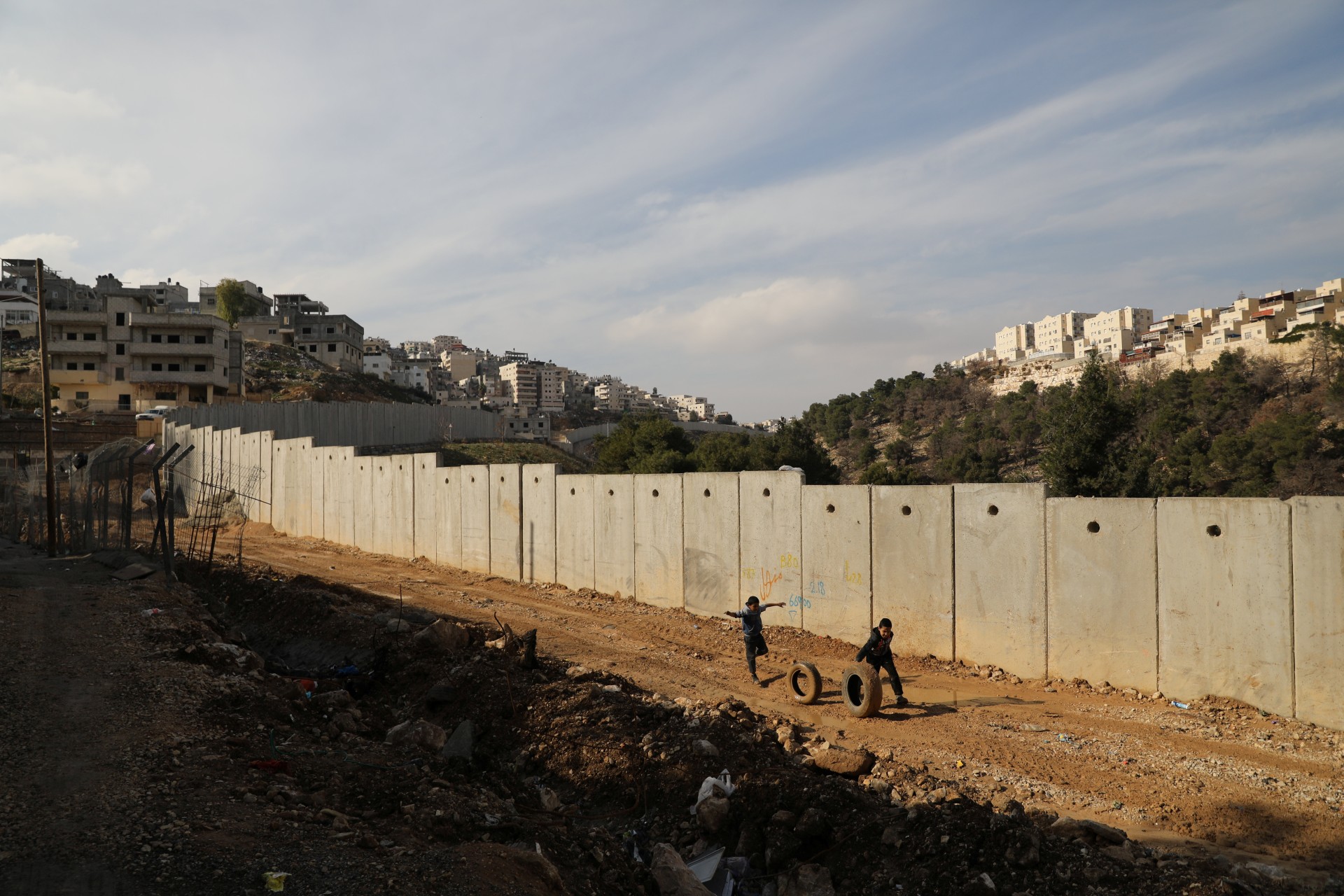 <p>Children roll tires as they run along the Israeli barrier in the East Jerusalem refugee camp of Shuafat (Ammar Awad/Reuters).</p>