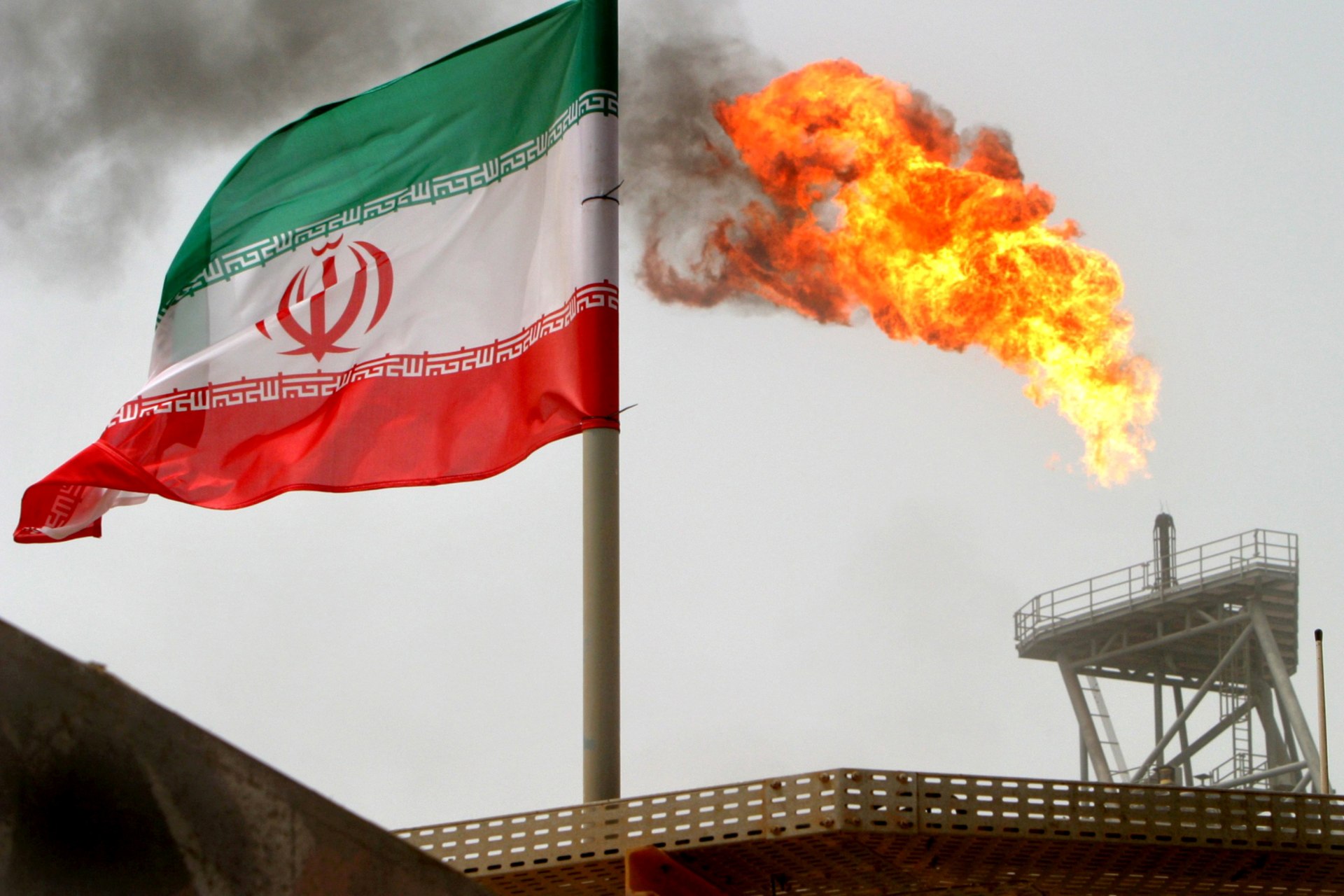 <p>A gas flare on an oil production platform is seen alongside an Iranian flag in the Gulf July 25, 2005. </p>
