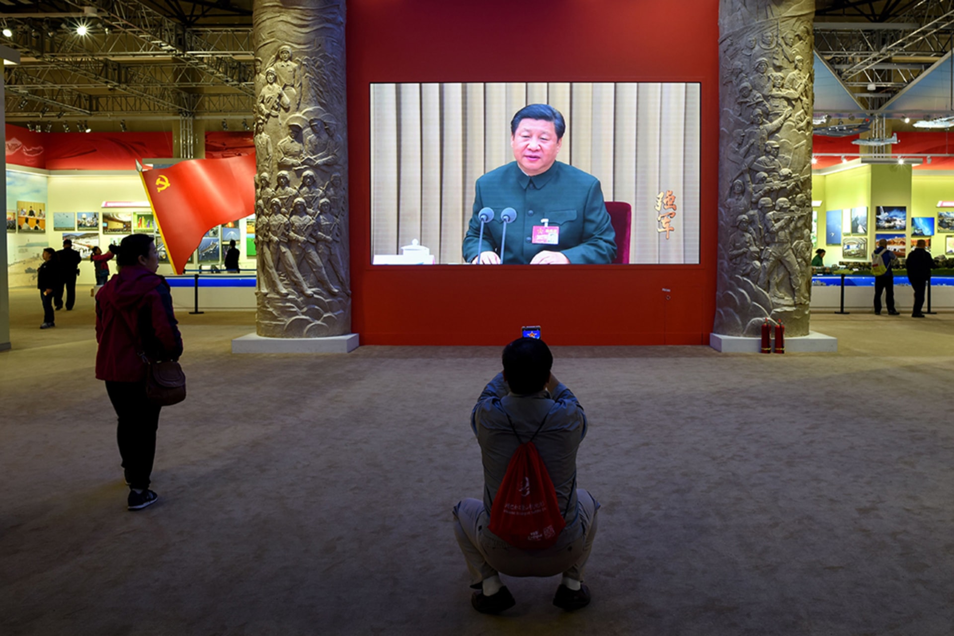 <p>A man takes a picture of a screen showing Chinese President Xi Jinping in October 2017.</p>