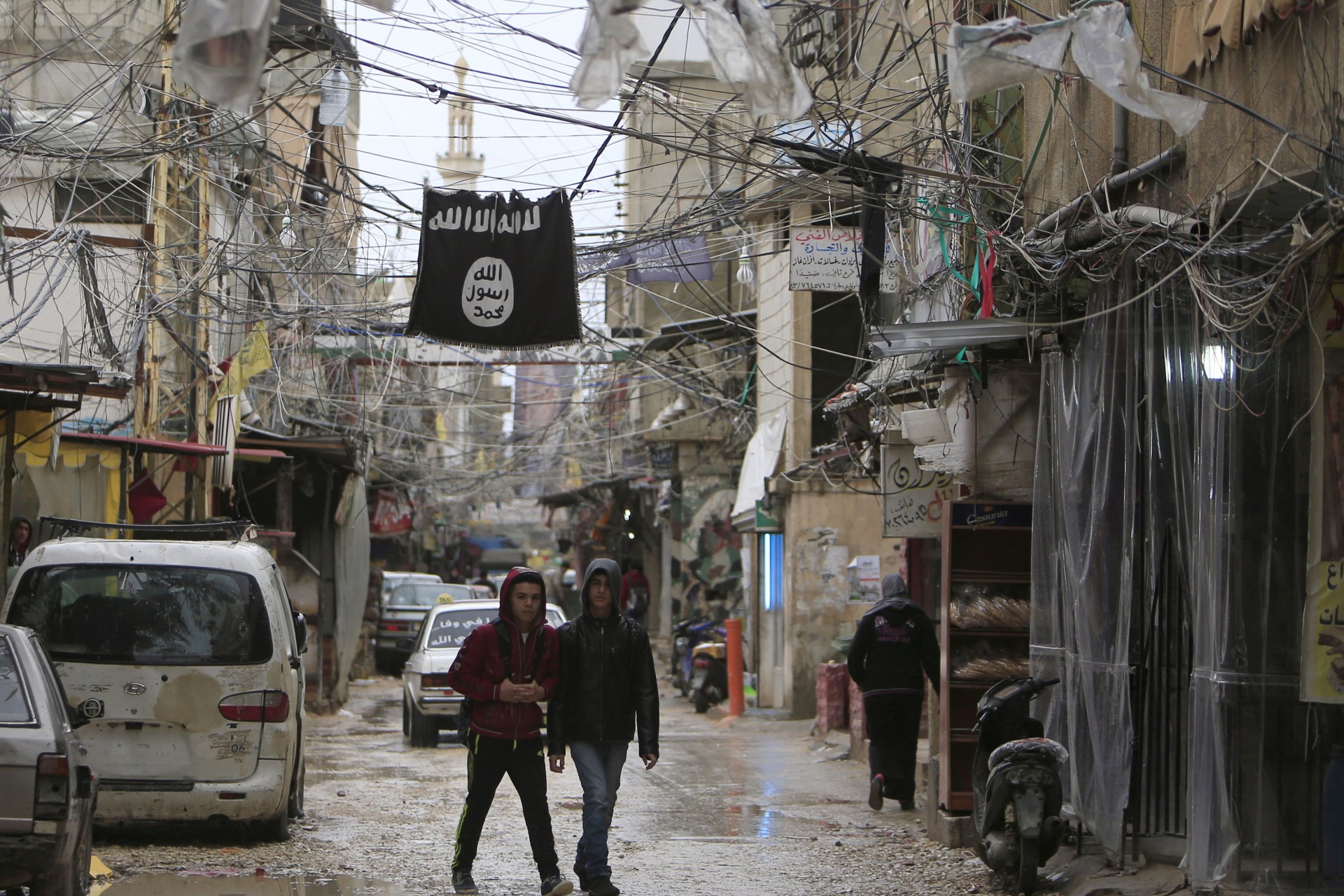 <p>Youth walk under an Islamic State flag in Ain al-Hilweh Palestinian refugee camp, near the port-city of Sidon, southern Lebanon January 19, 2016.</p>
