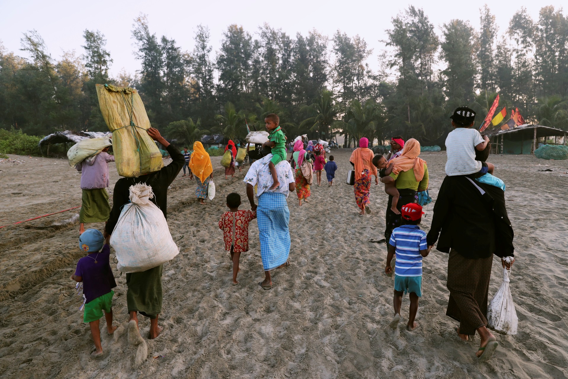 <p>A group of Rohingya refugees, who fled last night from Myanmar by boat, walk towards a makeshift camp in Cox’s Bazar, Bangladesh</p>
