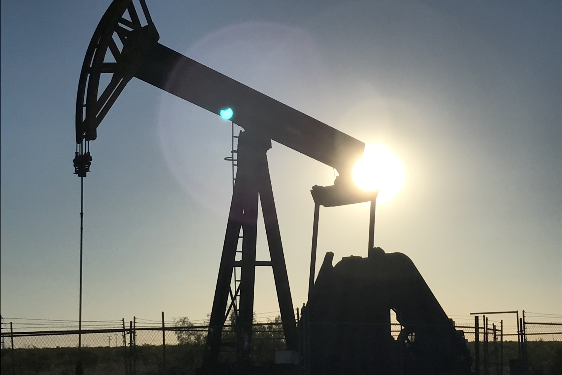 <p>An oil rig drilling a well at sunrise near Midland, Texas</p>