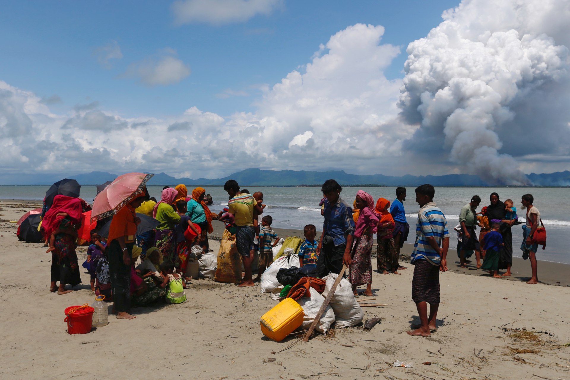 <p>Rohingya refugees watch the smoke on Myanmar border side after crossing the Bangladesh-Myanmar border by boat through the Bay of Bengal, in Shah Porir Dwip, Bangladesh on September 11, 2017.</p>
