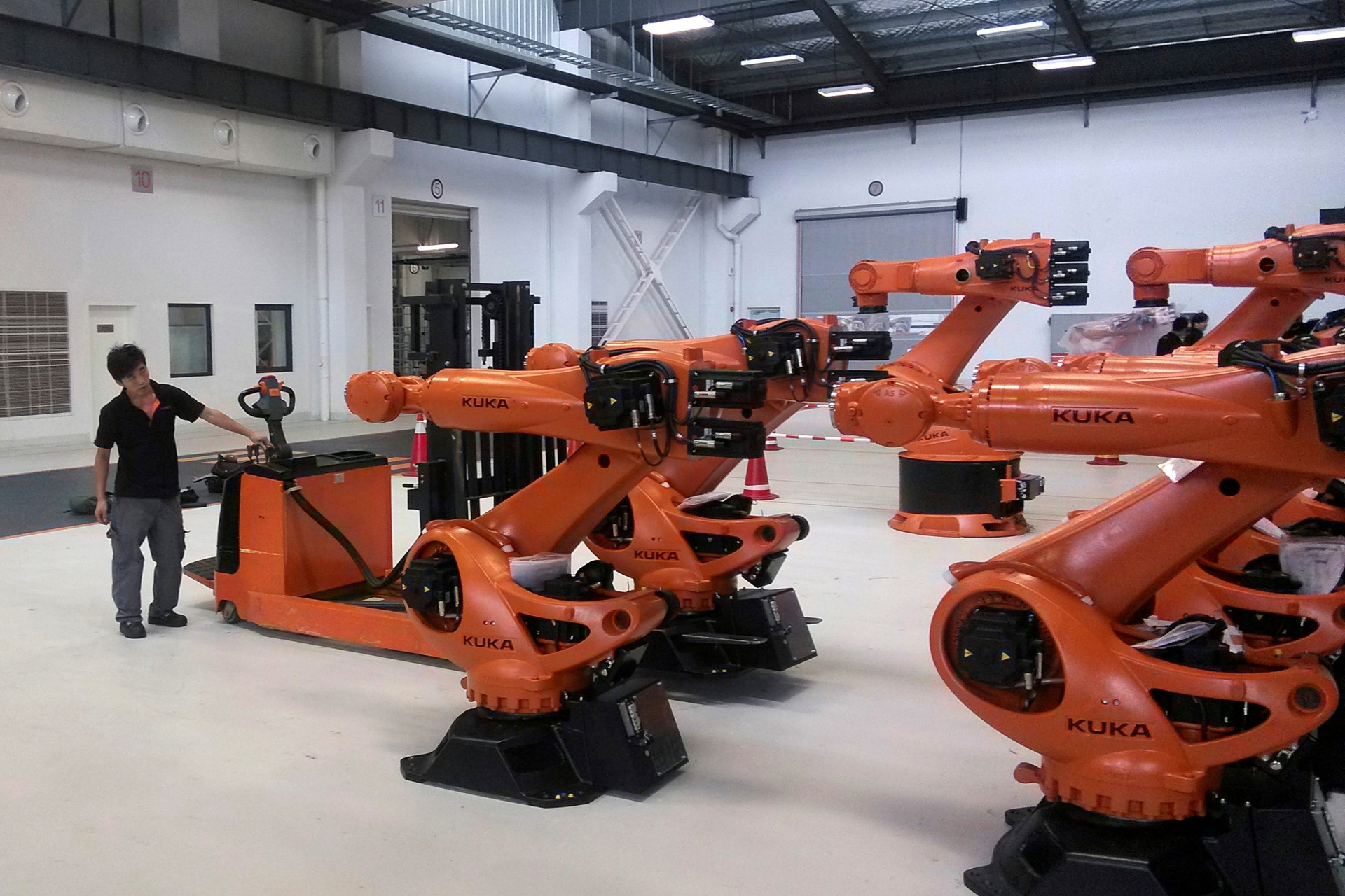 <p>A staff member stands next to robots at a plant of Kuka Robotics in Shanghai, China</p>