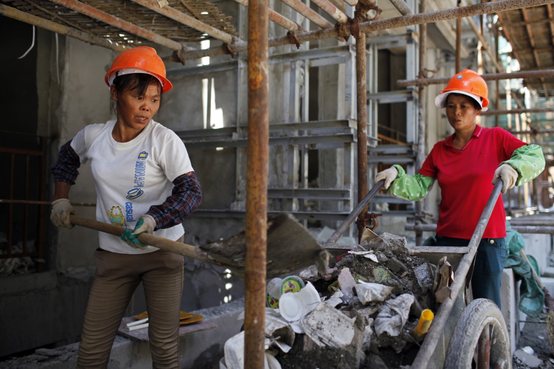 <p>Female migrant construction workers collect garbage onto a cart as they work on a shift at a residential construction site in Shanghai August 12, 2013.</p>