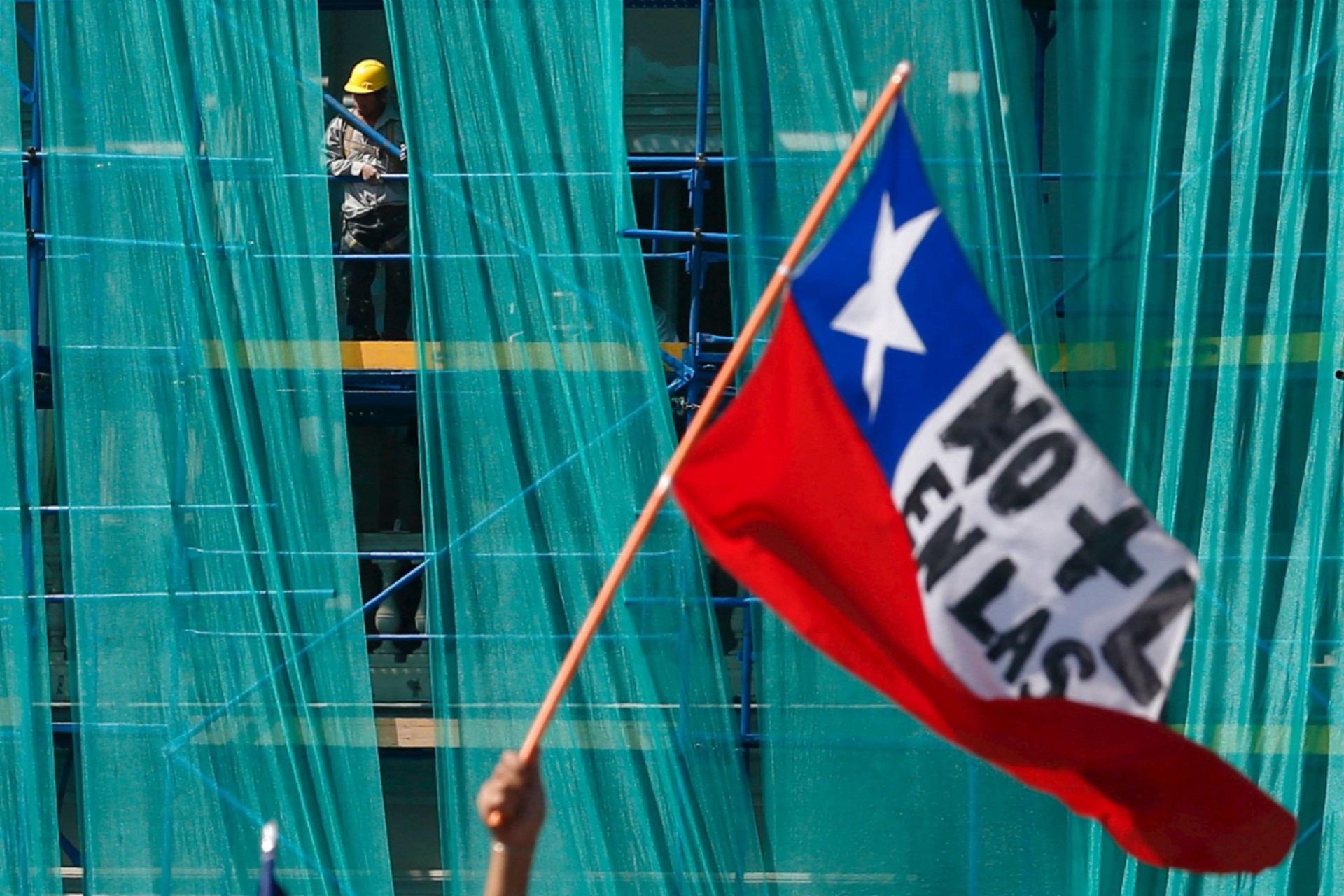 <p>A construction worker looks at workers from the public sector taking part in a rally against a new labour reform law promoted by the government that is pending in Congress in Santiago, Chile, March 22, 2016. </p>
