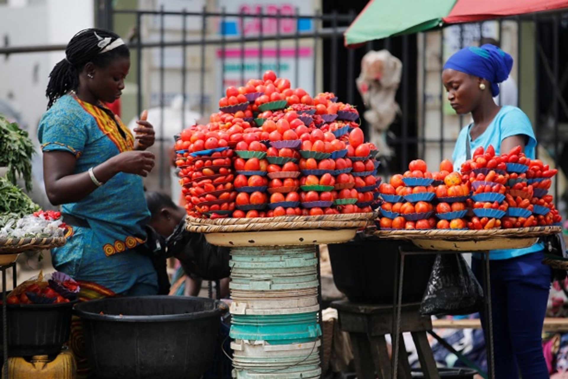 Women arrange produce for sale at a roadside market in Ojodu district in Lagos