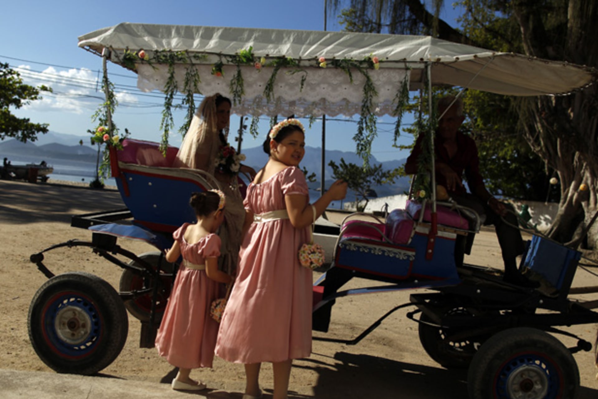 Flower girls wait next to the bride's carriage before a wedding ceremony on Paqueta island in Rio de Janeiro