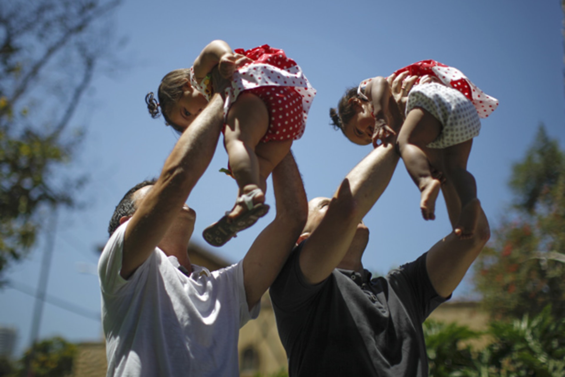 Jason Howe and Adrian Perez (L) hold their one-year-old twin daughters Clara (R) and Olivia at a playground in West Hollywood, California (Lucy Nicholson/Courtesy Reuters).