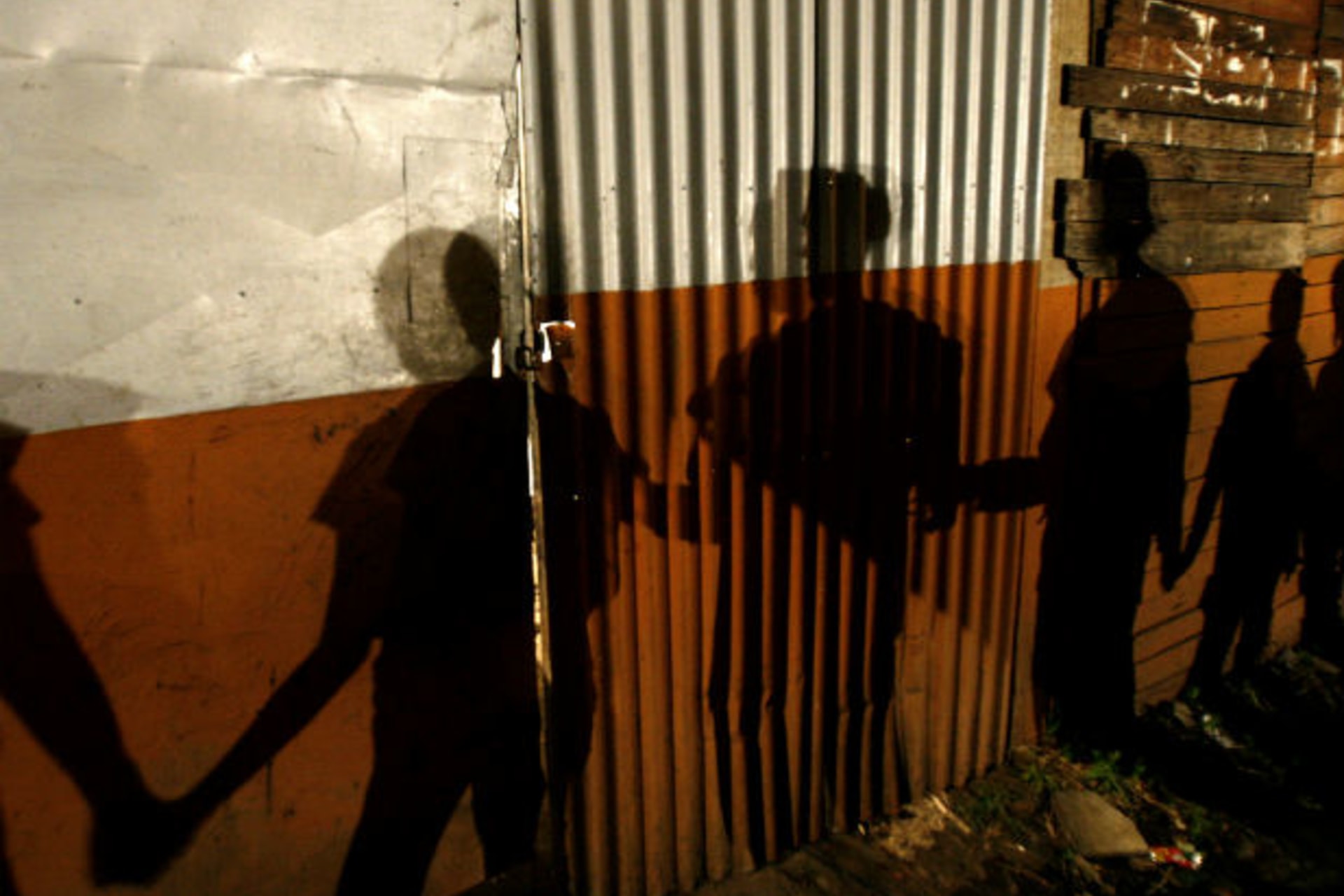 <p>Shadows on a slum wall are cast by Nicaraguan immigrants to Costa Rica during a prayer session in the neighborhood of Triangulo de la Solidaridad</p>
