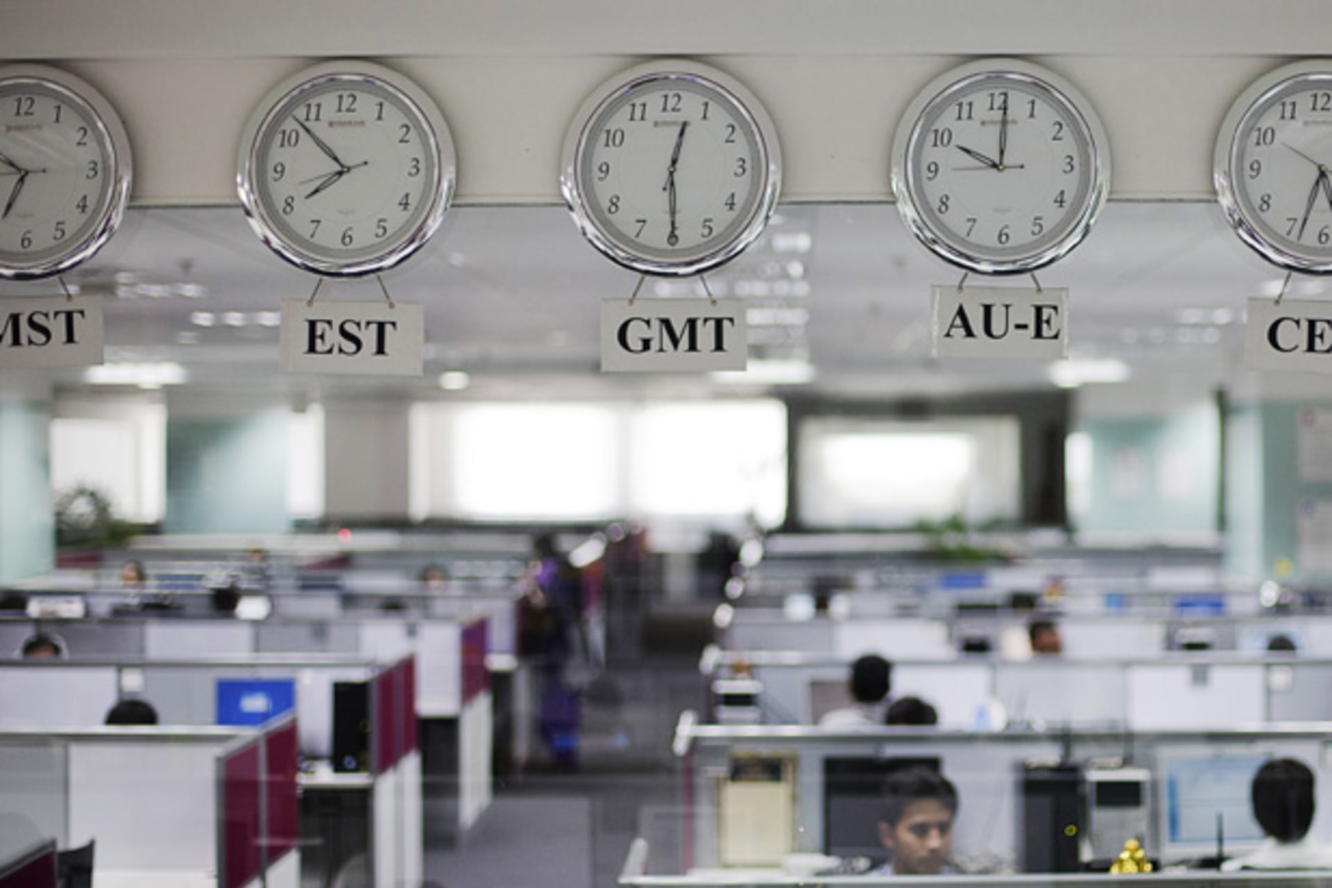 <p>Workers are pictured beneath clocks displaying time zones at an outsourcing center in Bangalore (Vivek Prakash/Courtesy Reuters).</p>
