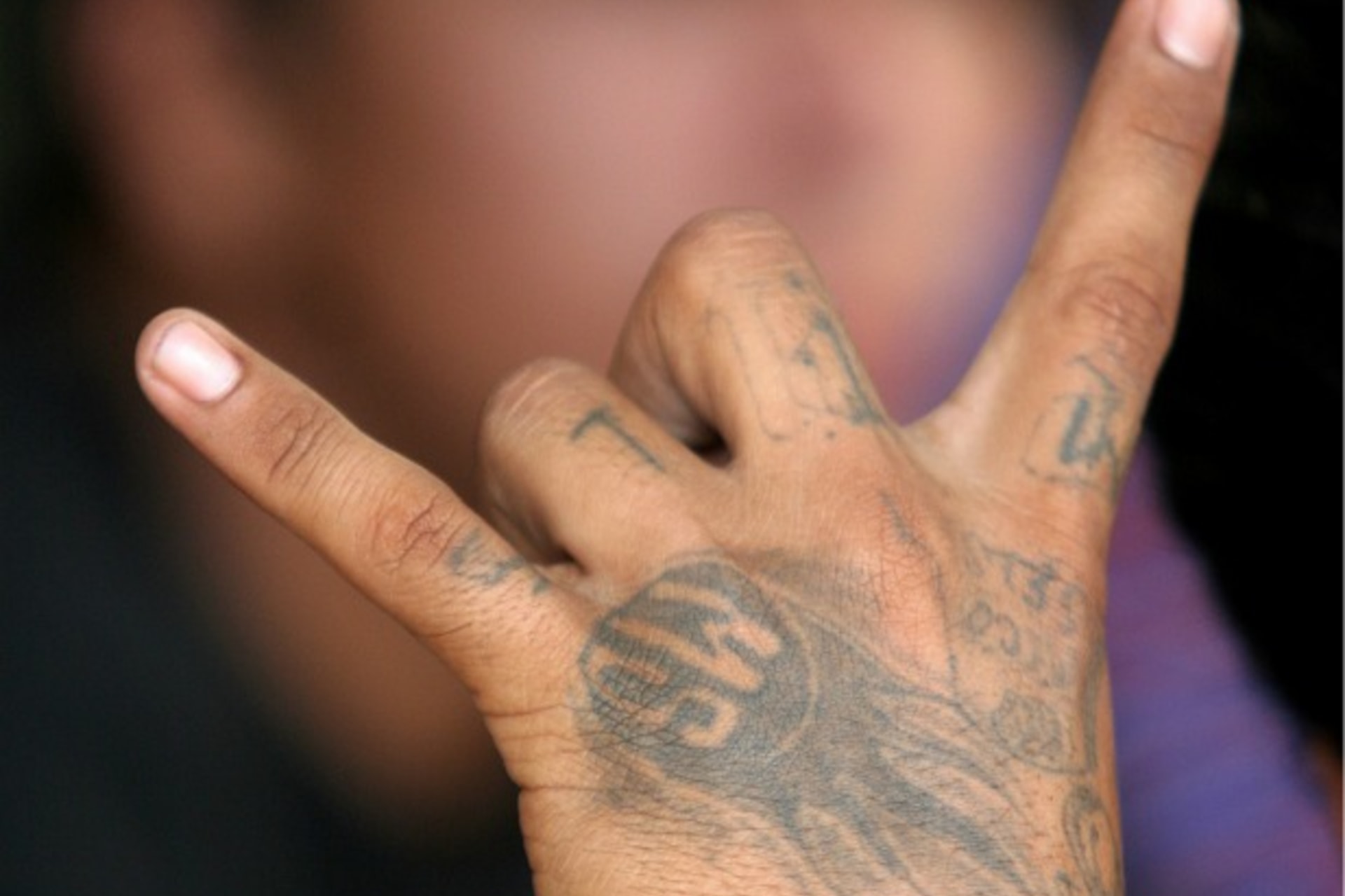 <p>A gang member flashes a gang sign as police parade suspected gang members they arrested in an overnight raid in San Salvador</p>
