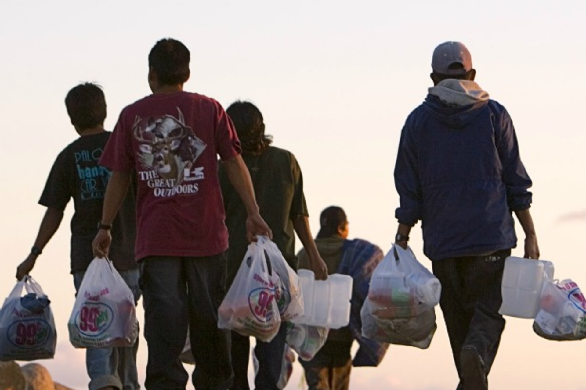 <p>Migrant farm workers walk back to their camp with food and other supplies in San Diego</p>

