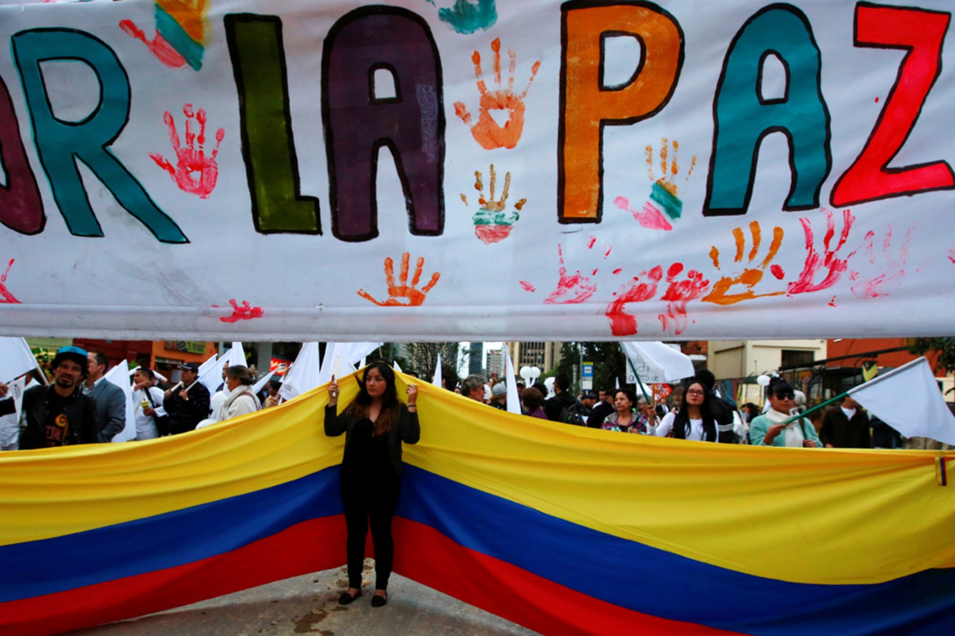 <p>A supporter rallying for a peace agreement between the Colombian government and FARC stands under a banner reading “for peace” during a march in Bogota.</p>
