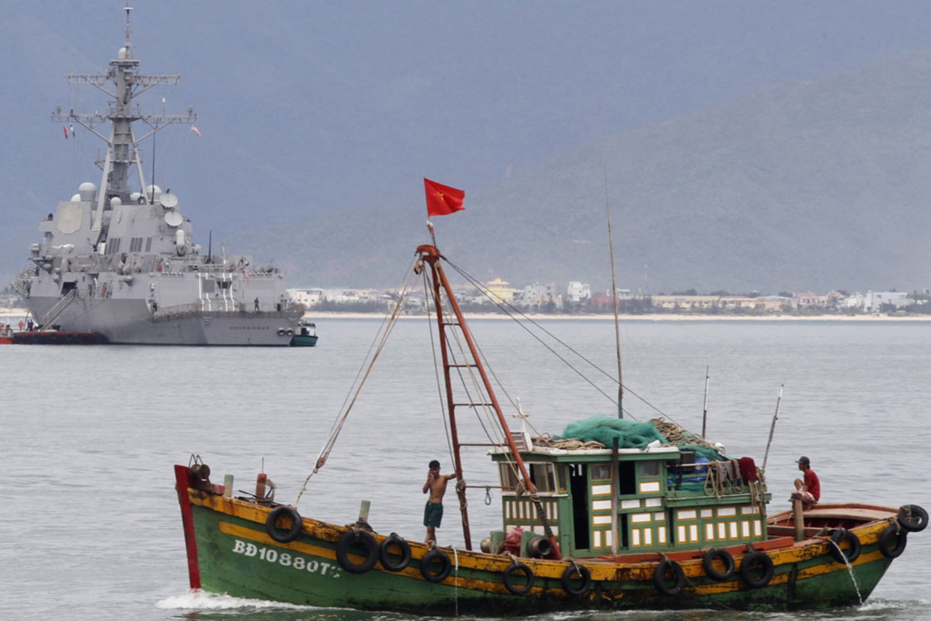 <p>A Vietnamese fishing boat goes past the USS Chung-Hoon at a port in Danang city, July 15, 2011.</p>
