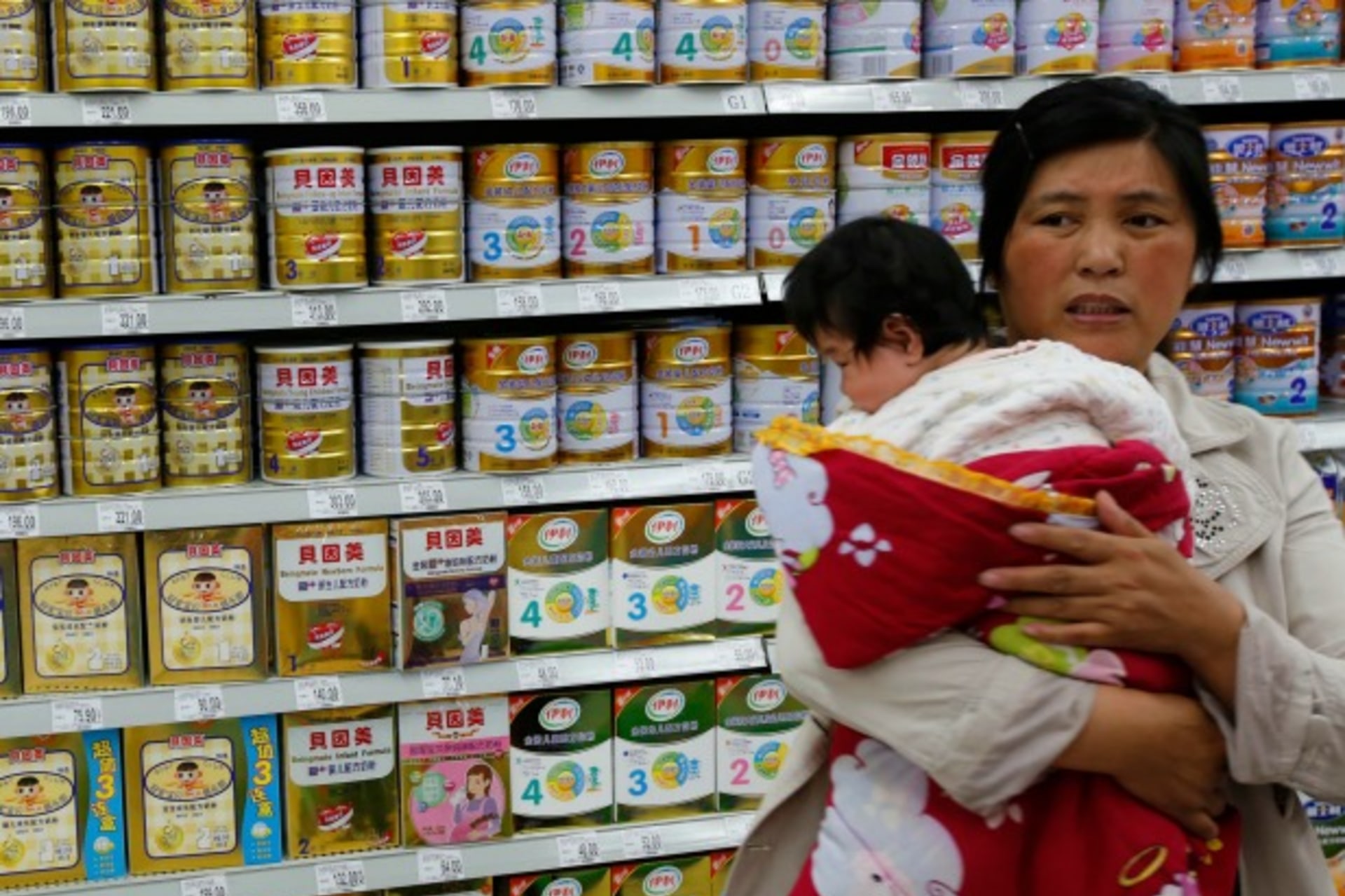 <p>A woman holding a baby stands in front of a shelf displaying milk powder products at a supermarket in Beijing May 20, 2013. (Kim Kyung Hoon/Courtesy Reuters)</p>
