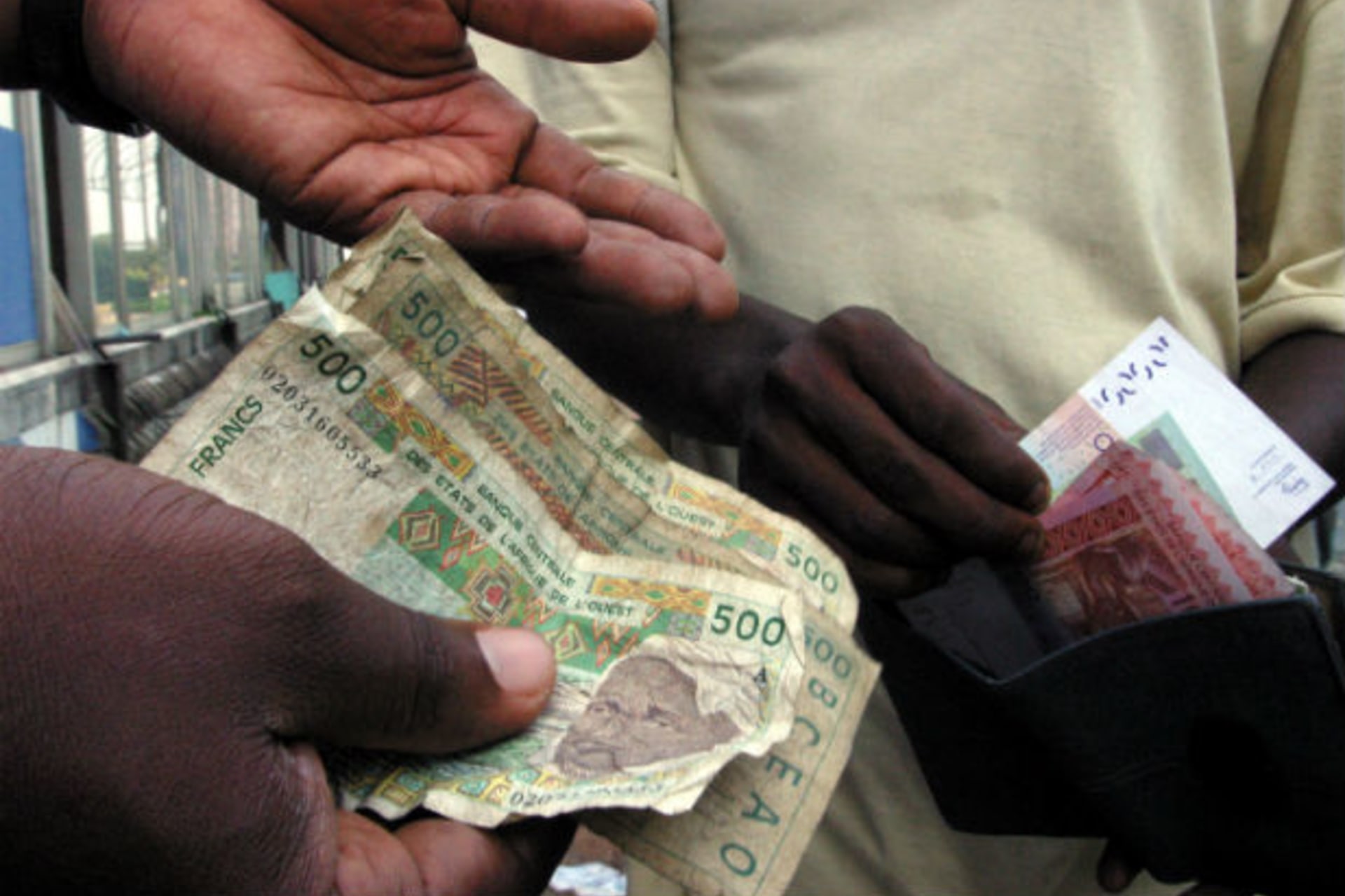People exchange money in Abidjan, December 31, 2004.