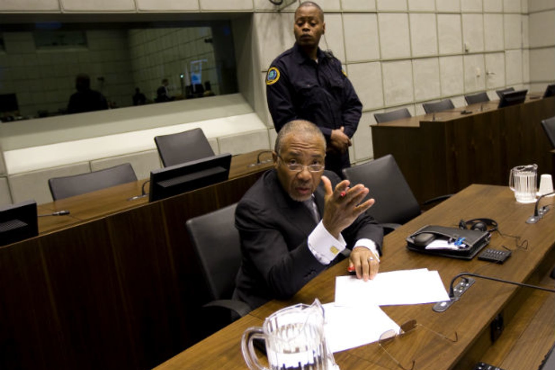 Former Liberian President Charles Taylor (bottom) argues with a photographer as he awaits the start of the prosecution's closing arguments during his trial at the U.N.-backed Special Court for Sierra Leone in Leidschendam February 8, 2011.