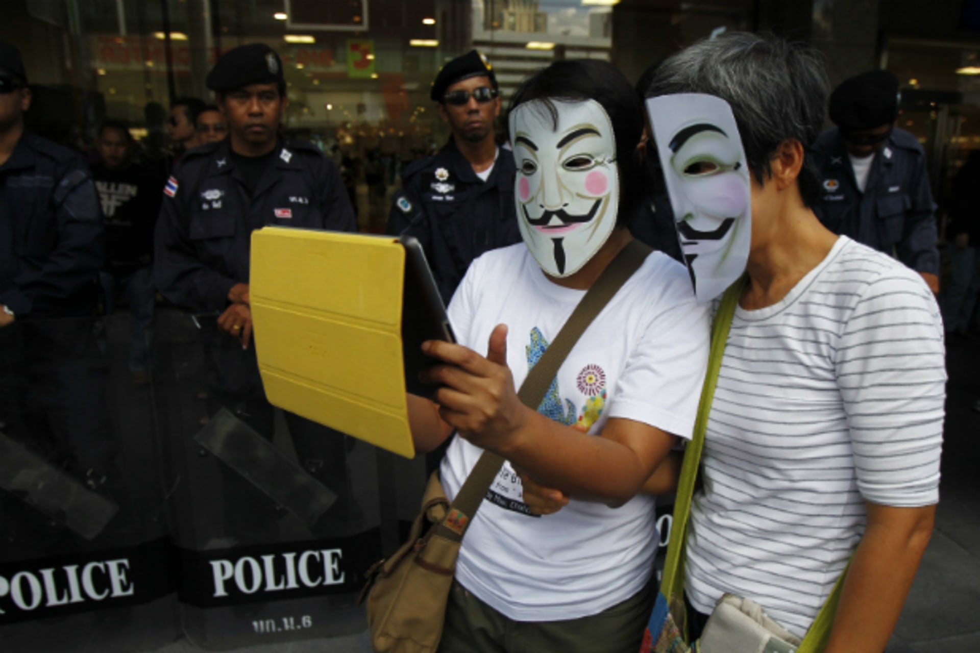 <p>Anti-government protesters wearing Guy Fawkes masks use an iPad in front of riot policemen during a rally outside a shopping mall in Bangkok on June 9, 2013. (Chaiwat Subprasom/Courtesy Reuters)</p>

