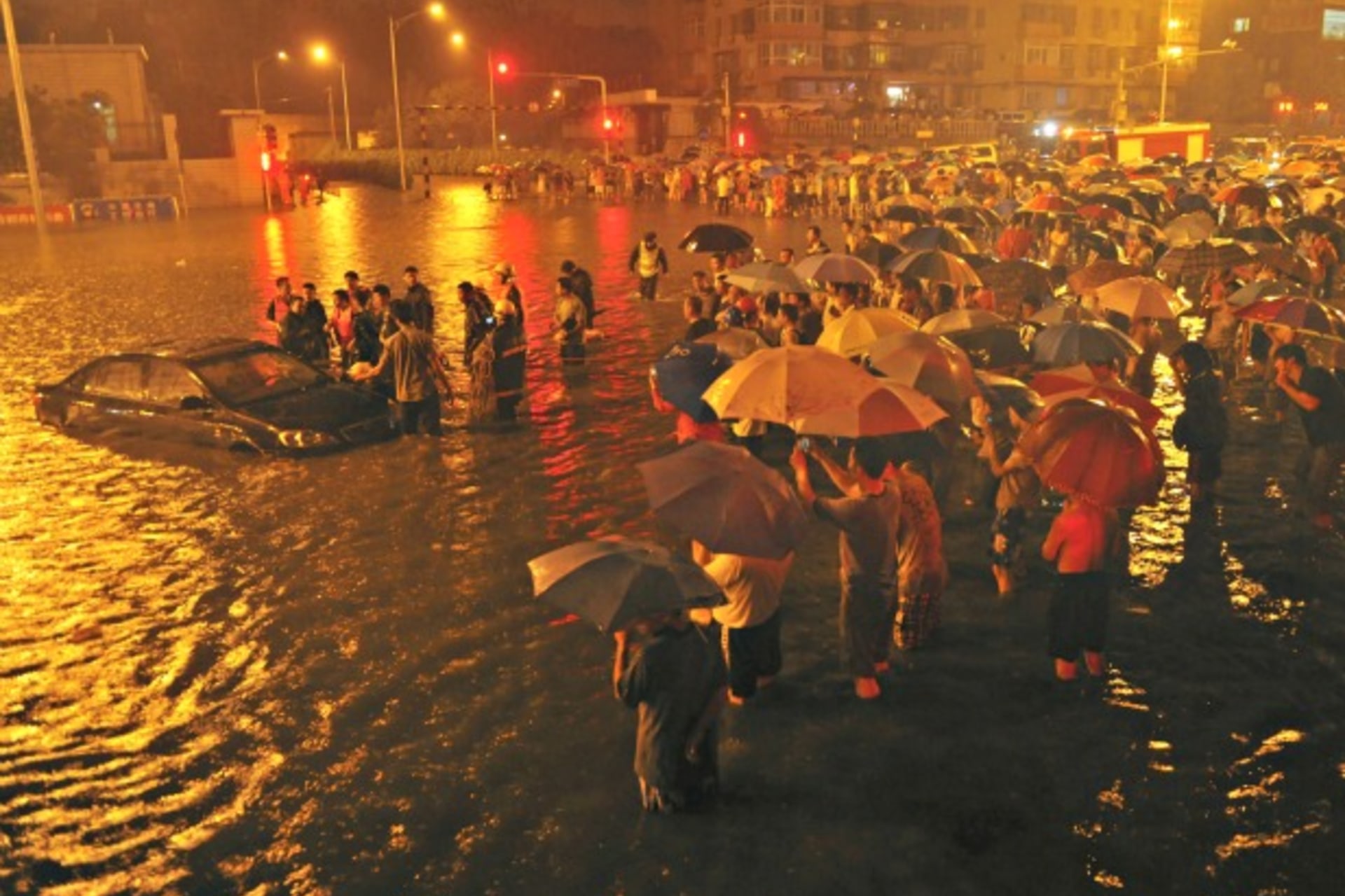 <p>Rescuers and residents stand next to a stranded car which is being pulled up from a flooded street under the Guangqumen overpass amid heavy rainfalls in Beijing on July 21, 2012.</p>
