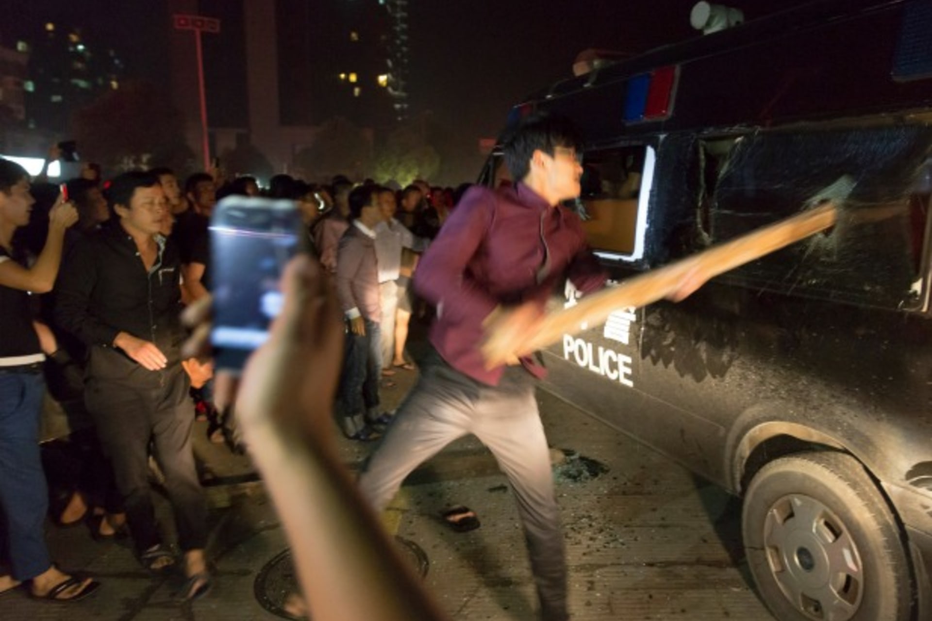 <p>A man breaks the window of a police van with a wooden plank during a protest in Yuyao, Zhejiang province, on October 11, 2013. (Young/Courtesy Reuters)</p>