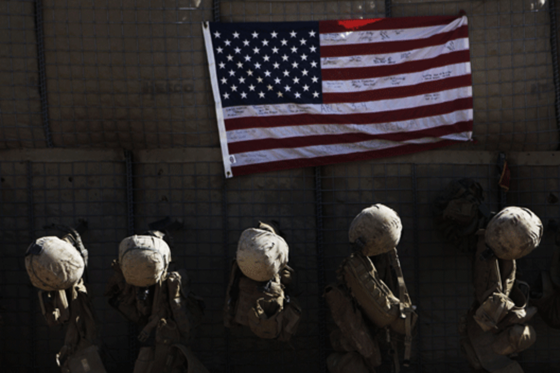 <p>Equipment belonging to U.S. Marines hang by a flag at their outpost in Afghanistan’s Helmand province. (Finbarr O’Reilly/courtesy Reuters)</p>
