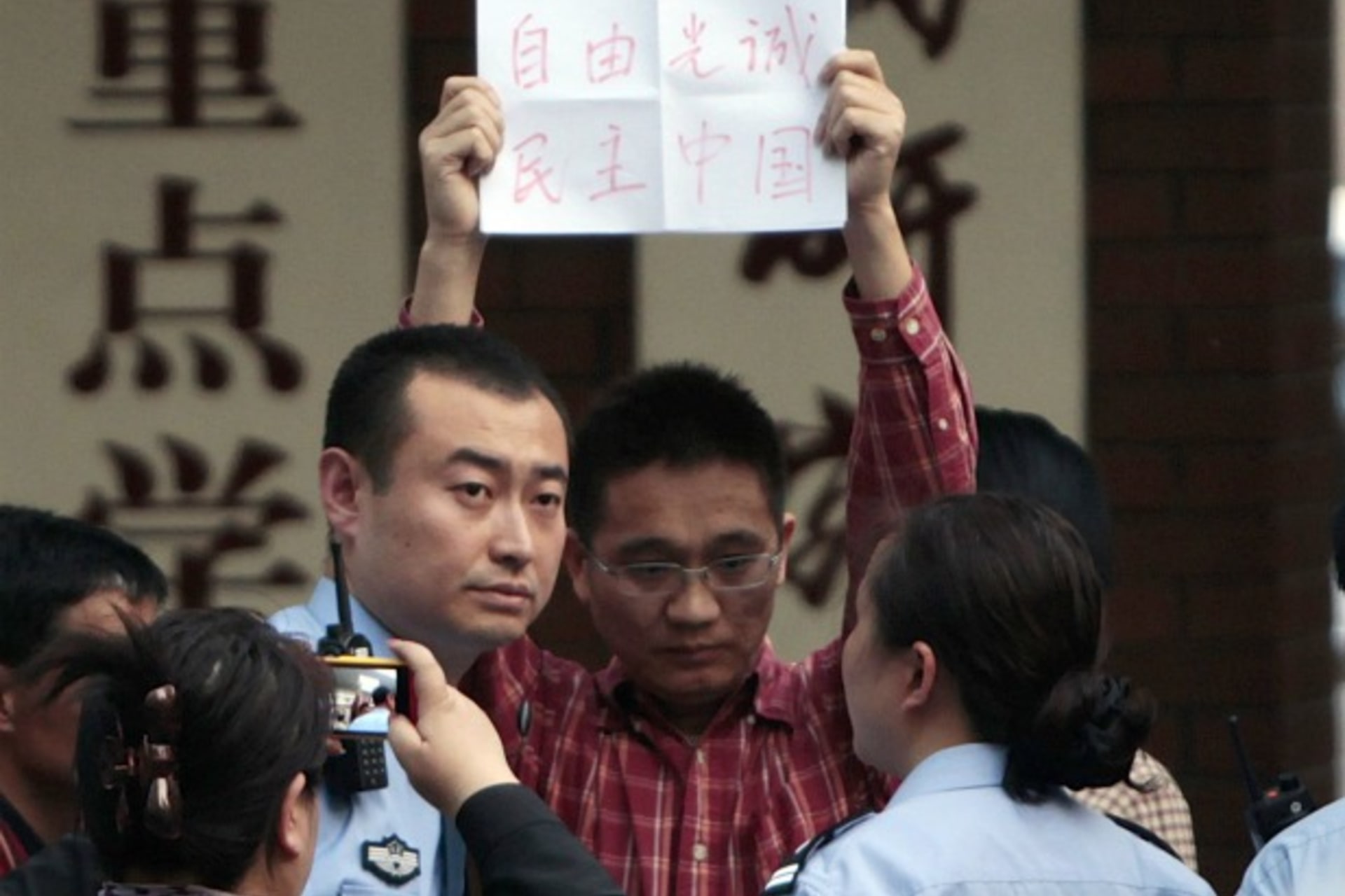 <p>A supporter of Chen Guangcheng holds up a piece of paper reading, “Freedom, Guangcheng, Democracy, China”, as he is being take…lice officers at Chaoyang Hospital in Beijing, where blind activist Chen Guangcheng was reported to be staying on May 2, 2012.</p>
