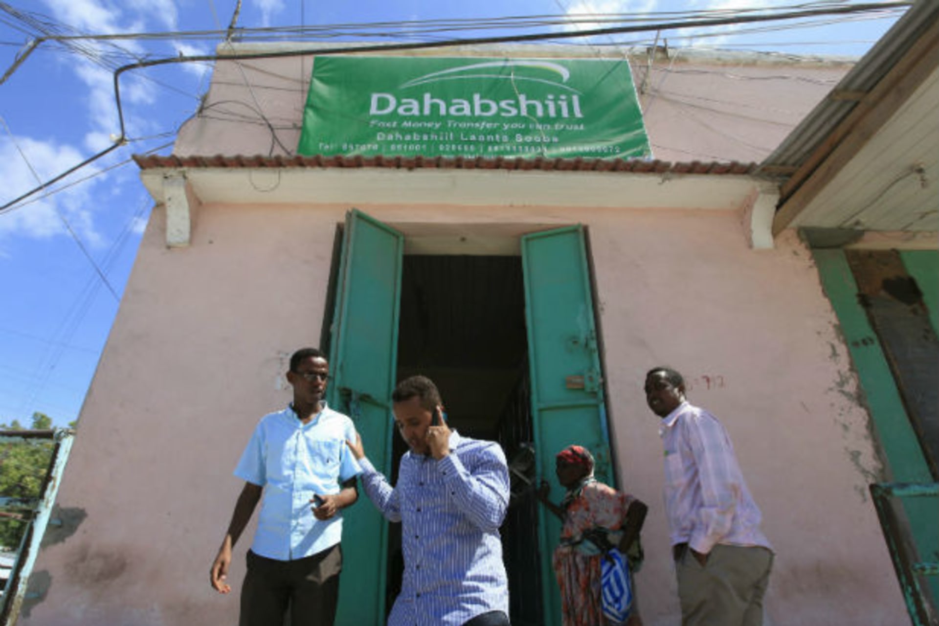 Customers walk out of a Dahabshiil money transfer office in "Kilometer Five" street of Soobe village, southern Mogadishu, May 8, 2013.