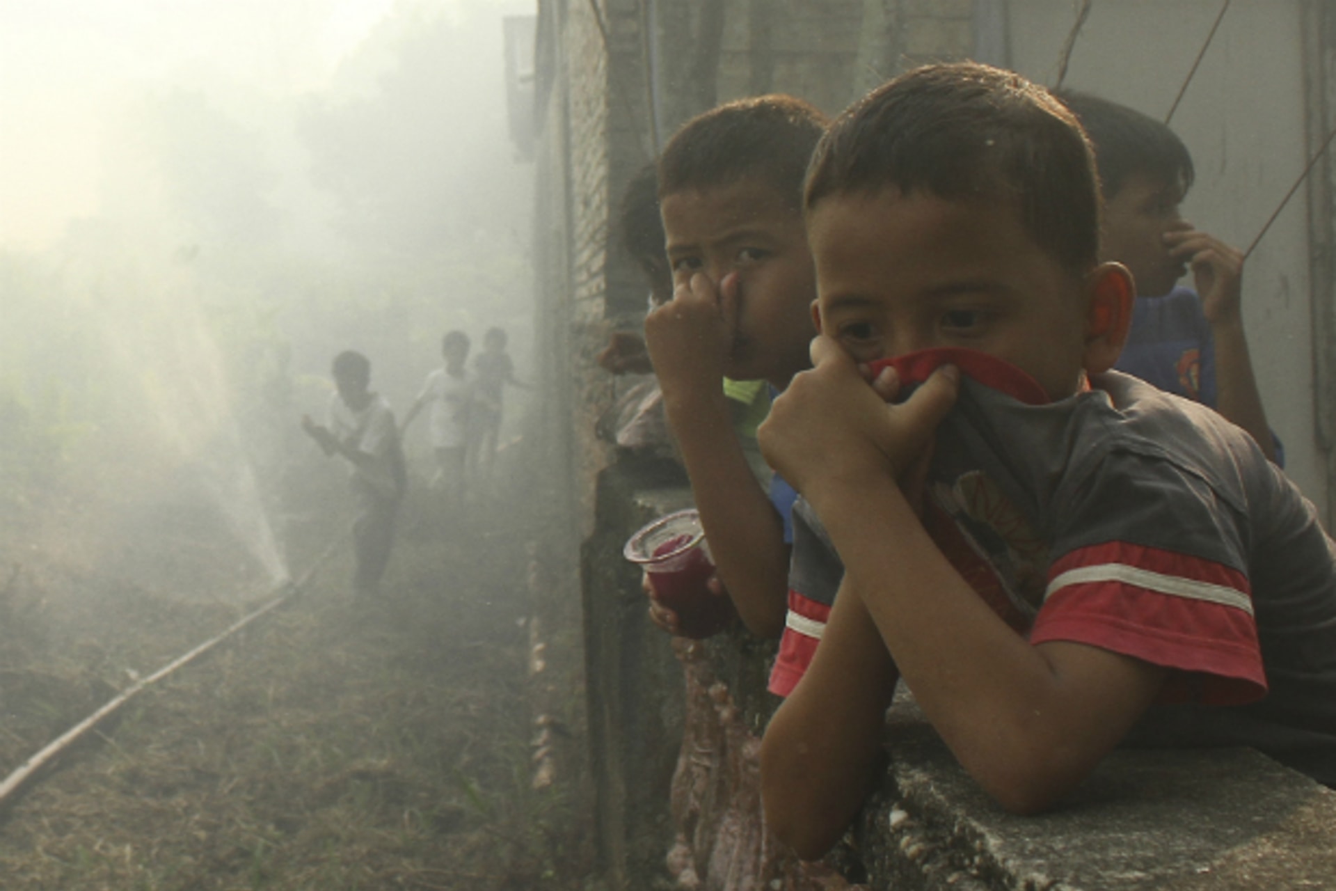 <p>Children cover their noses near burnt land in Marpoyan Damai sub district, in the outskirts of Pekanbaru, in Indonesia’s Riau province on June 20, 2013. (Stringer Indonesia/Courtesy Reuters)</p>
